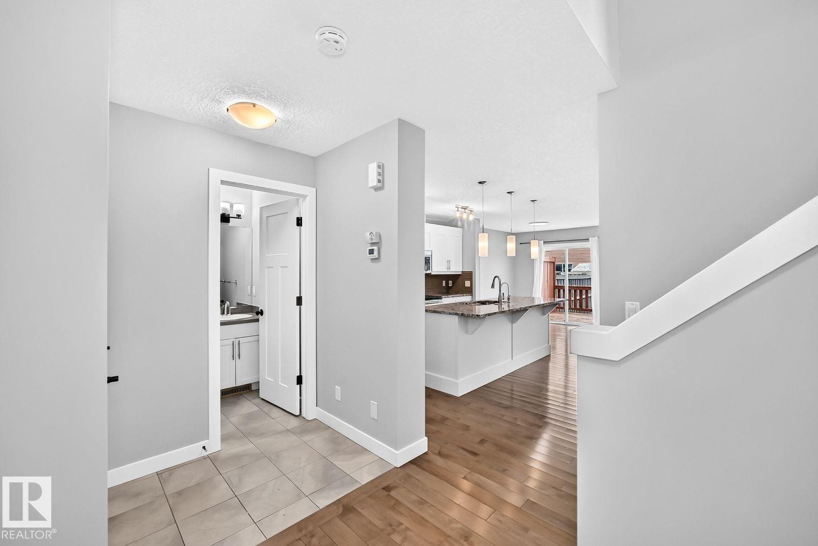Wood-finish flooring throughout the main living areas - 1112 176 Street Sw, Edmonton, AB - Indoor Photo Showing Other Room
