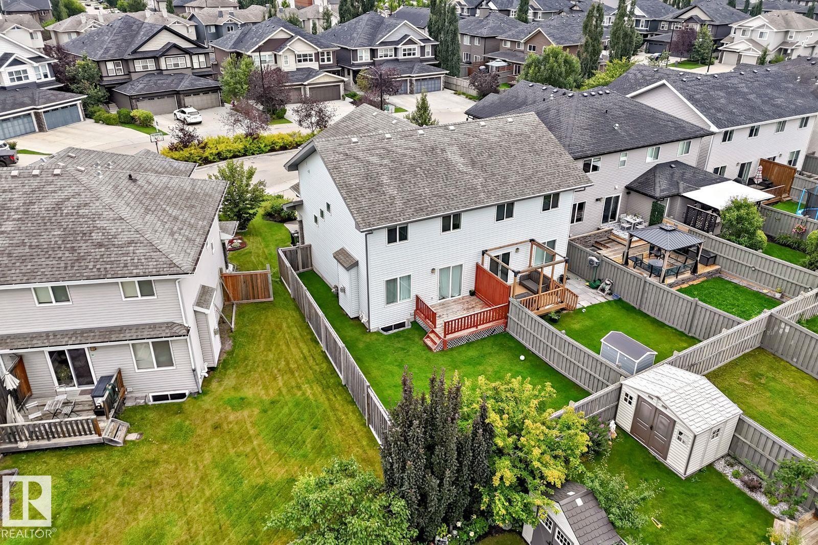Rear exterior with white siding, wood deck, and fenced backyard - 1112 176 Street Sw, Edmonton, AB - Outdoor