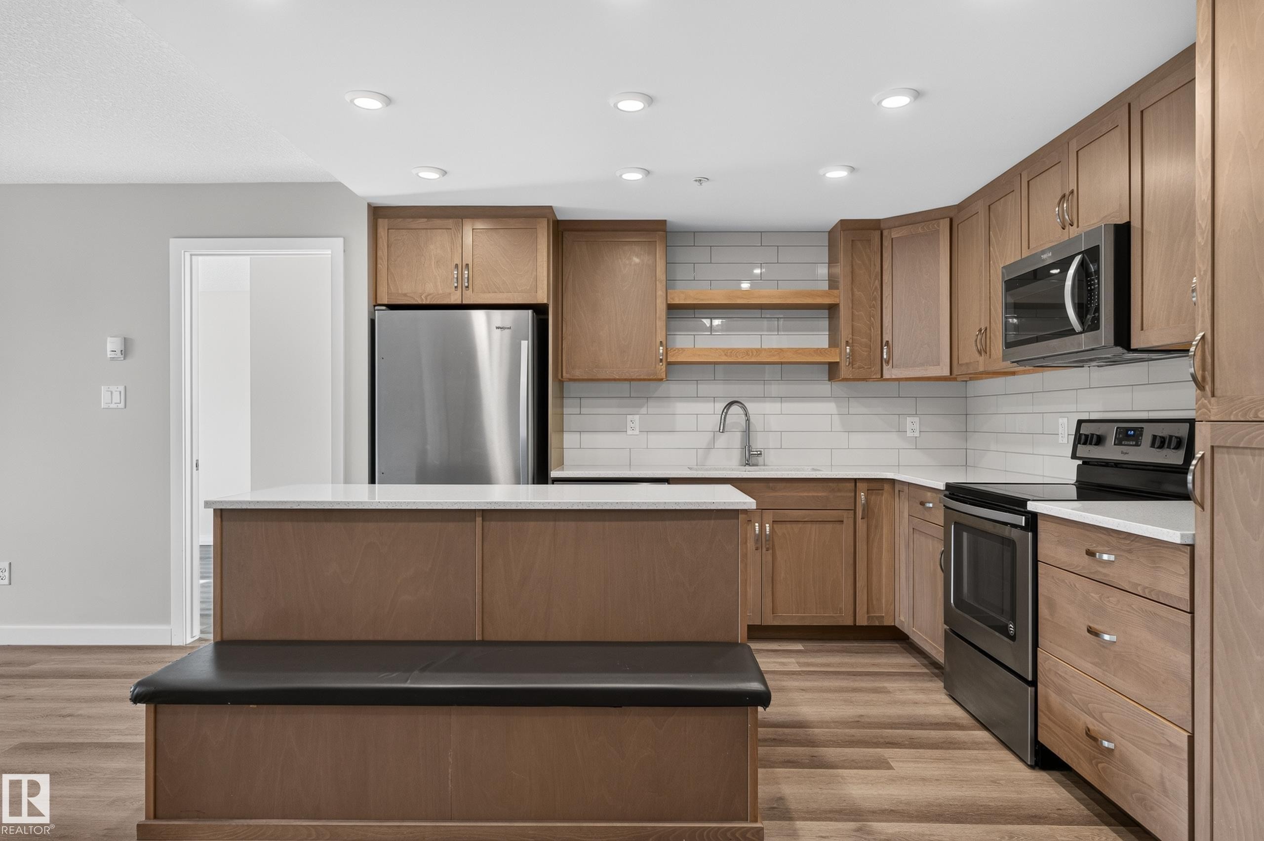 Kitchen featuring stainless steel appliances, wood-finish cabinetry, white subway tile backsplash, recessed lighting, and wood-finish flooring - #131 5504 Schonsee Dr Nw, Edmonton, AB - Indoor Photo Showing Kitchen