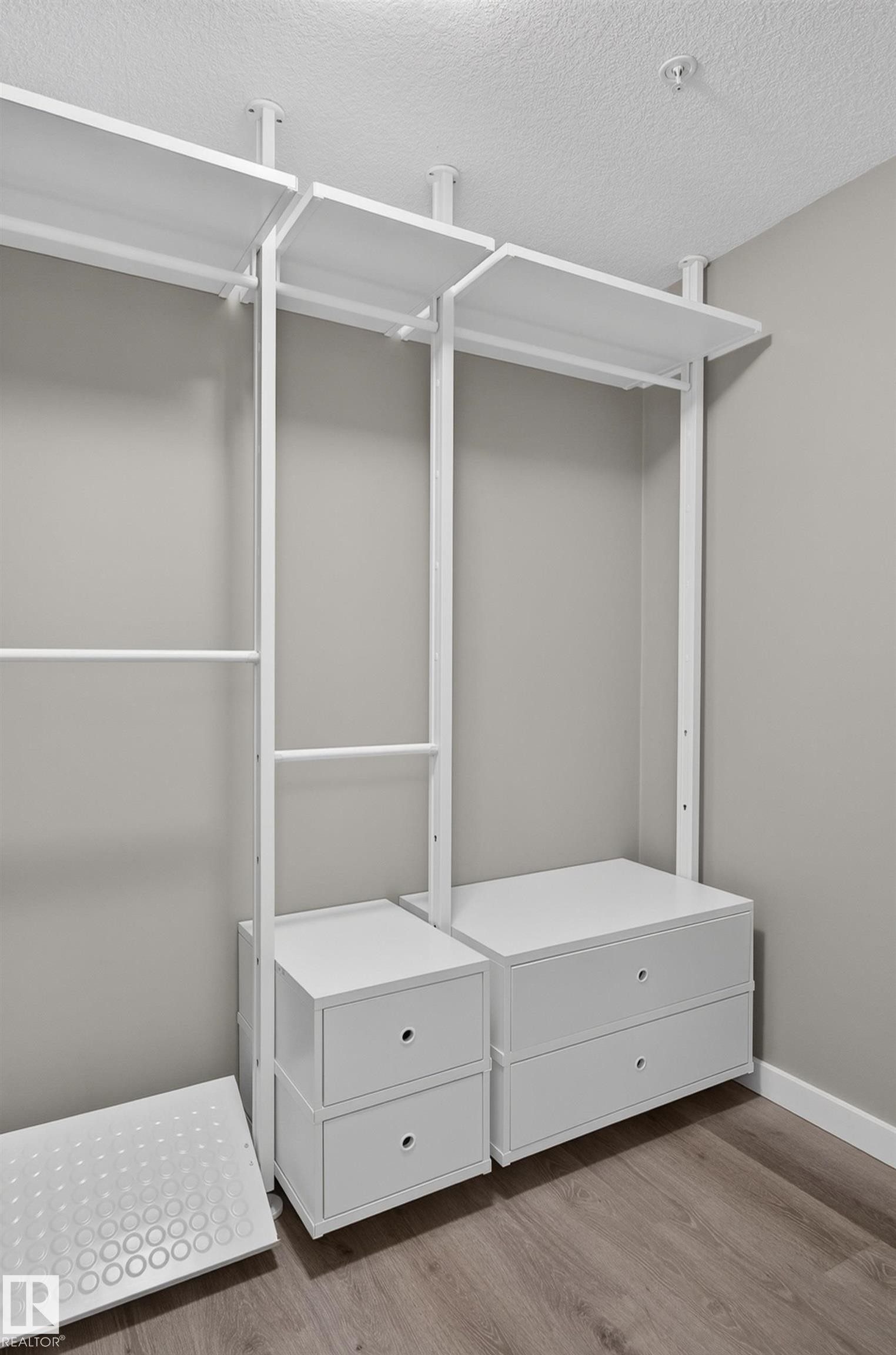 Integrated white closet organization system with hanging rods, shelving, and pull-out drawers - #131 5504 Schonsee Dr Nw, Edmonton, AB - Indoor