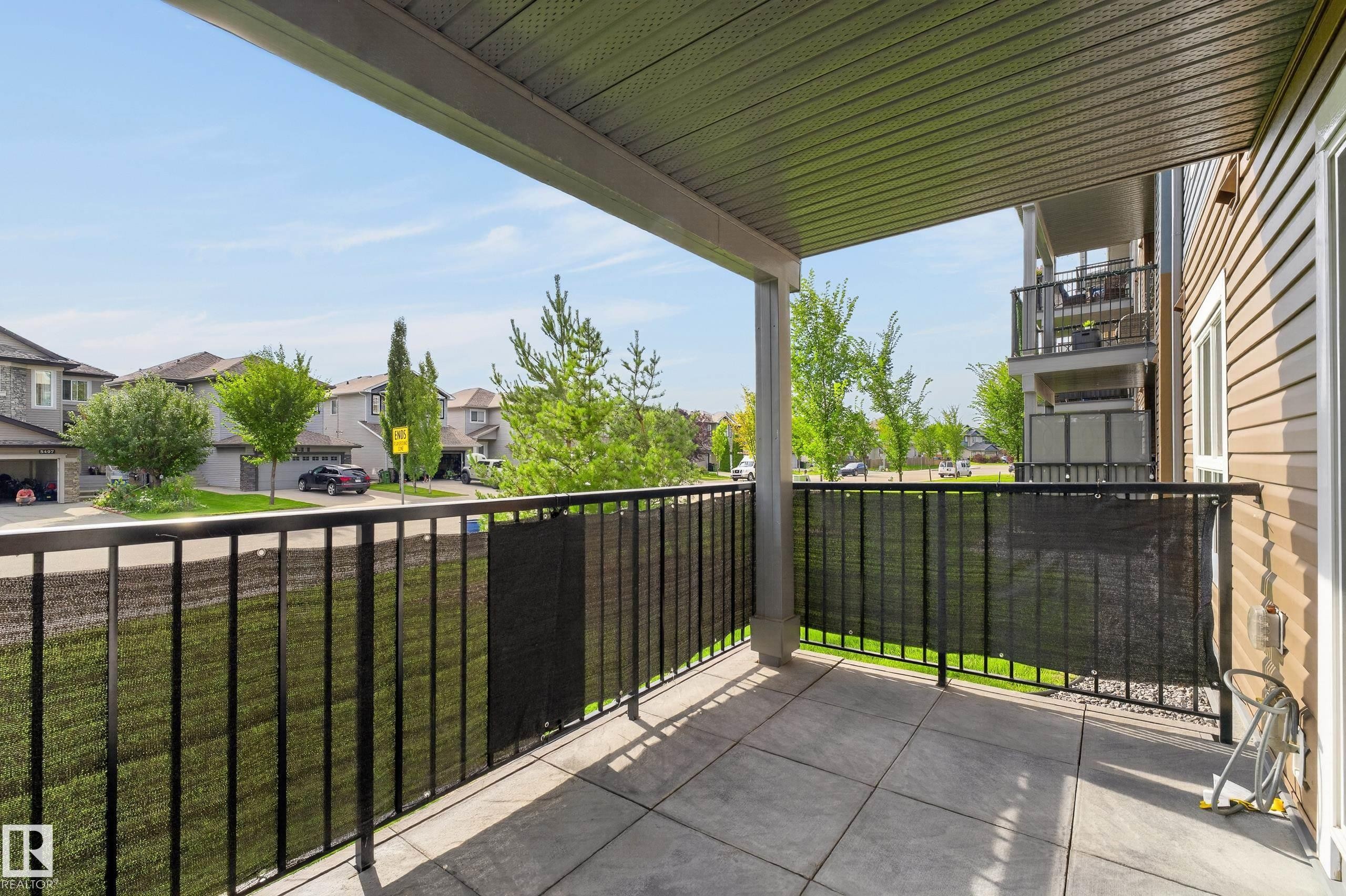 Covered outdoor patio with a concrete surface and a black metal railing - #131 5504 Schonsee Dr Nw, Edmonton, AB - Outdoor With Balcony With Exterior