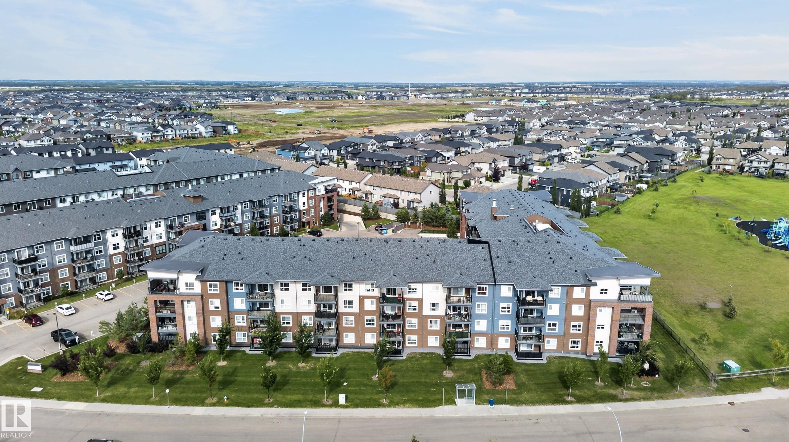 Modern apartment complex with multi-story facades, individual balconies, and surrounding green spaces - #131 5504 Schonsee Dr Nw, Edmonton, AB - Outdoor With View