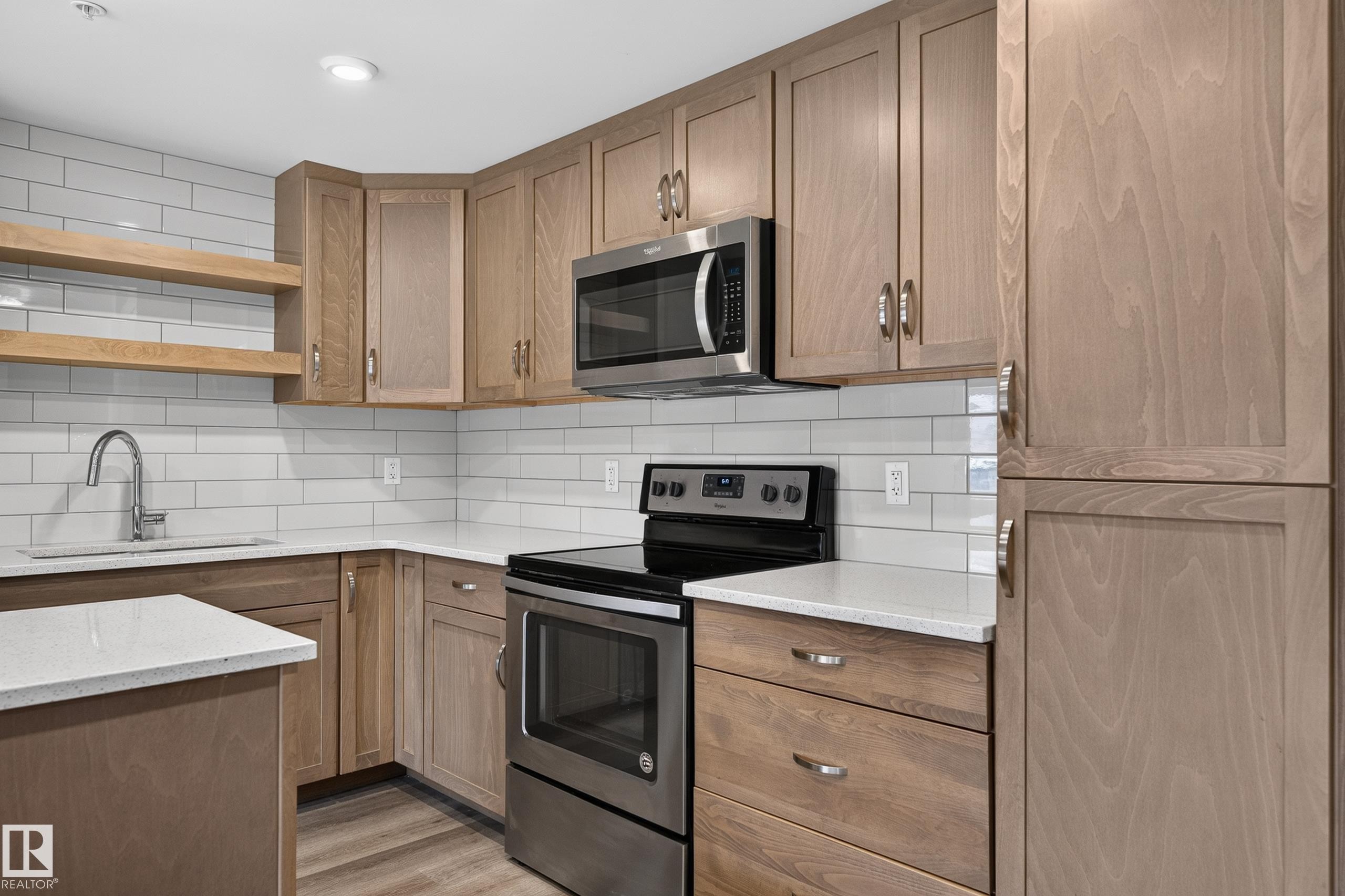 Stainless steel appliances, wood-finish cabinetry, white subway tile backsplash, light-toned countertops, and an undermount sink - #131 5504 Schonsee Dr Nw, Edmonton, AB - Indoor Photo Showing Kitchen With Upgraded Kitchen