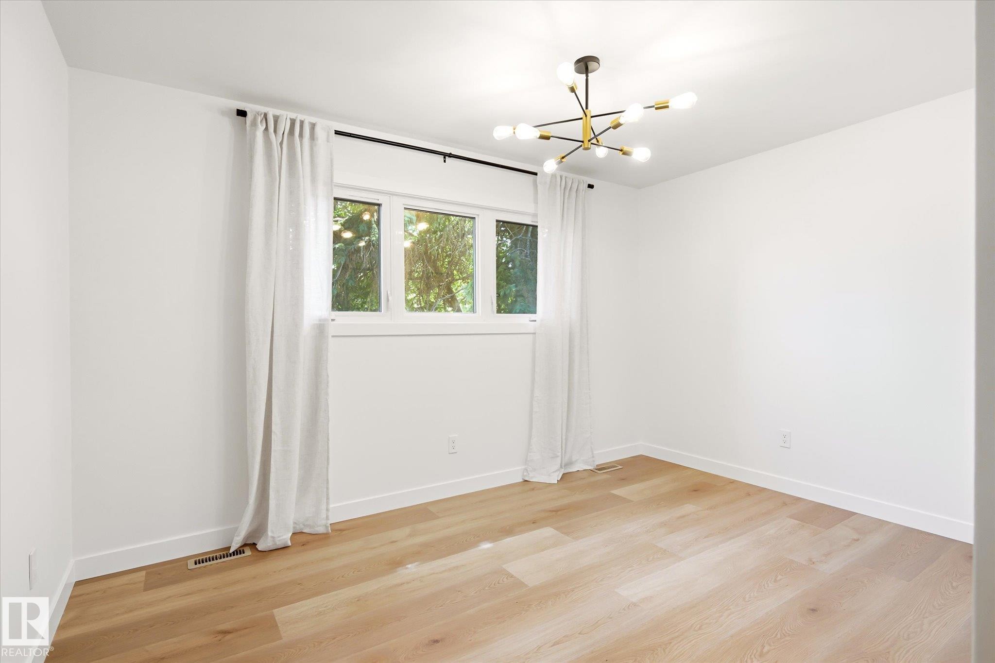 Neutral interior featuring light wood-finish flooring, white walls, and a modern sputnik chandelier - 4708 104A Avenue Nw, Edmonton, AB - Indoor Photo Showing Other Room