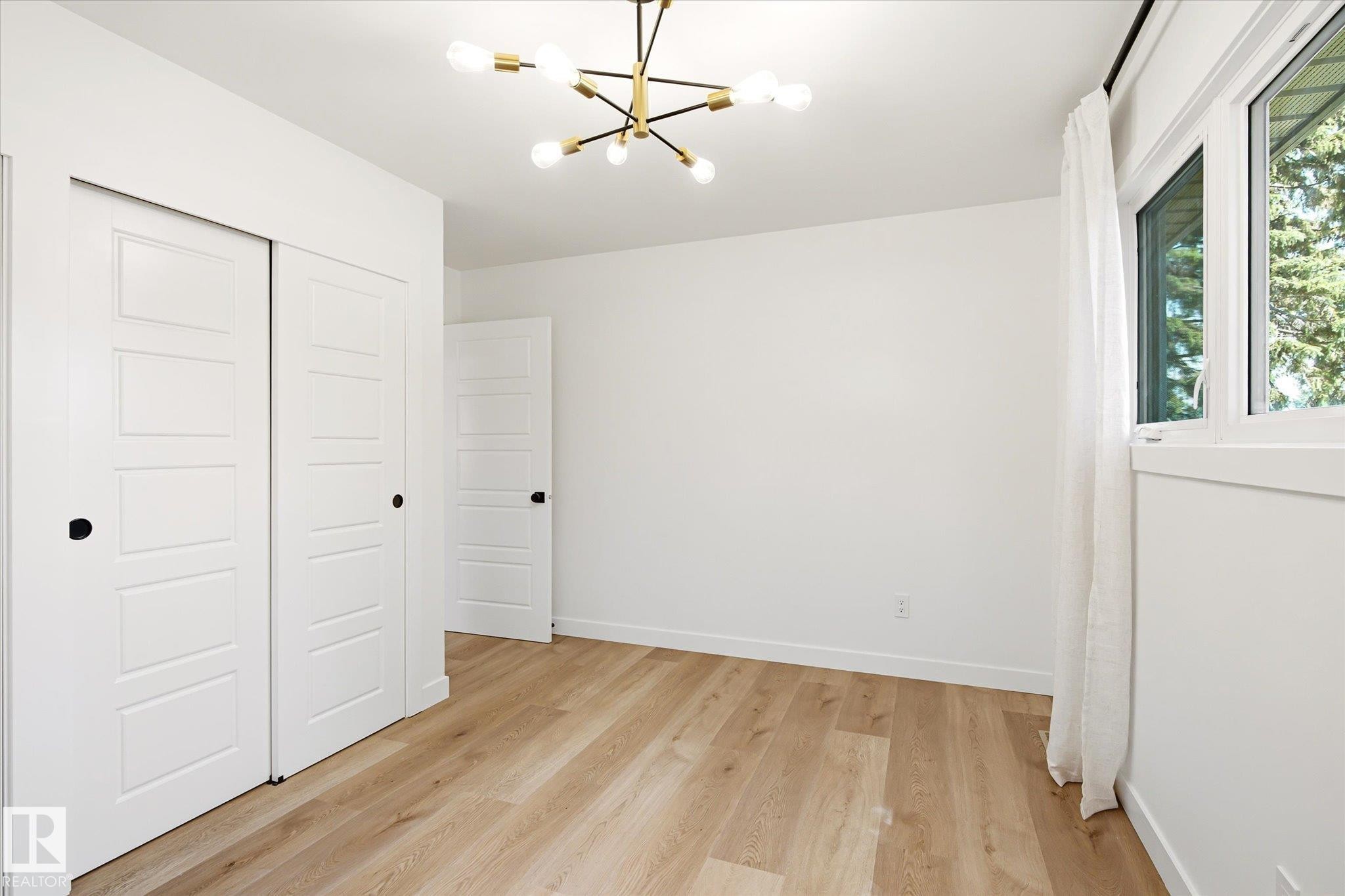 Bright room with wood-finish flooring and a contemporary sputnik chandelier - 4708 104A Avenue Nw, Edmonton, AB - Indoor Photo Showing Other Room