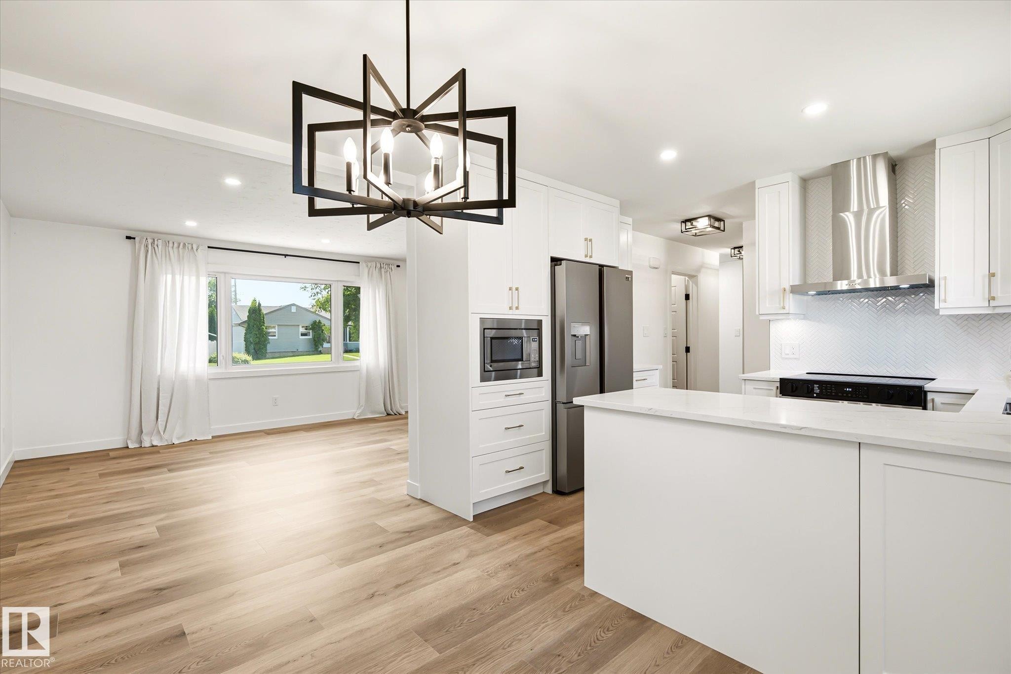 Open-concept living space with wood-finish flooring, recessed lighting, and a contemporary black chandelier - 4708 104A Avenue Nw, Edmonton, AB - Indoor Photo Showing Kitchen