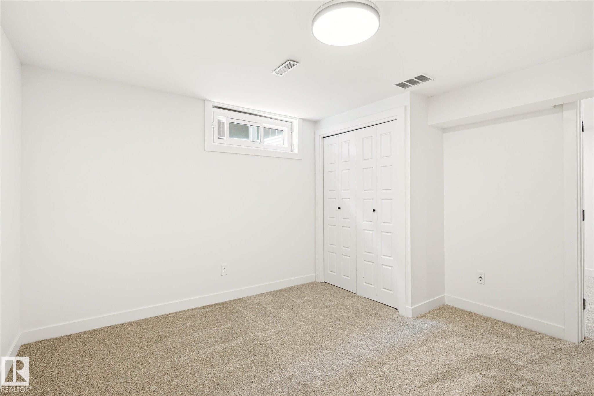 Bright room with carpet flooring, a window, bifold closet doors, and recessed lighting - 4708 104A Avenue Nw, Edmonton, AB - Indoor Photo Showing Other Room
