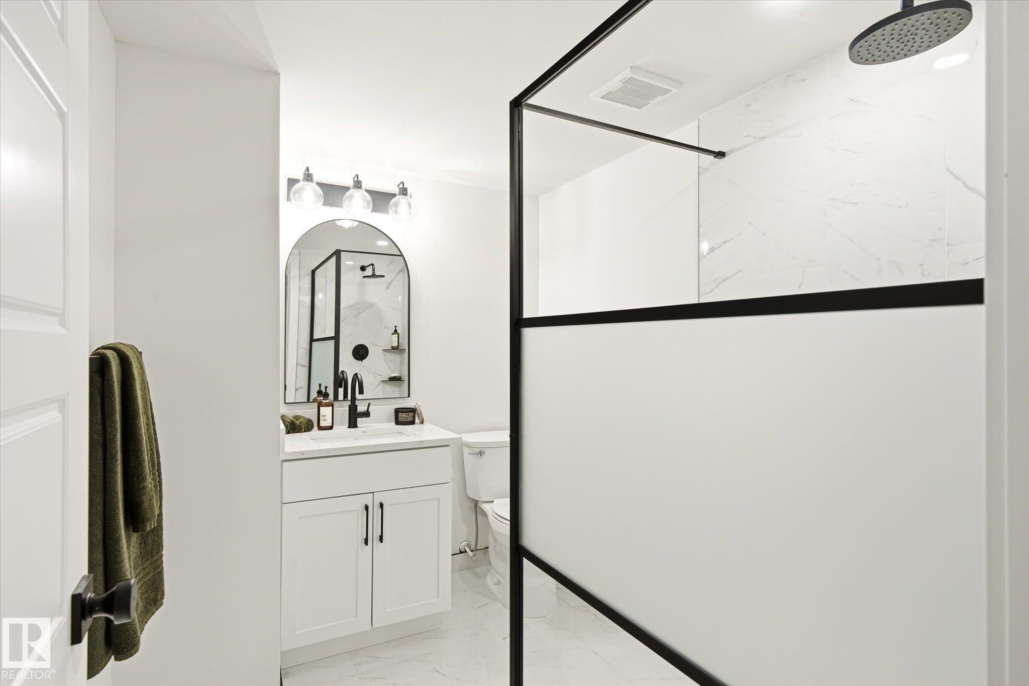 Modern bathroom featuring a walk-in shower with a black-framed opaque panel and a rainfall showerhead - 4708 104A Avenue Nw, Edmonton, AB - Indoor