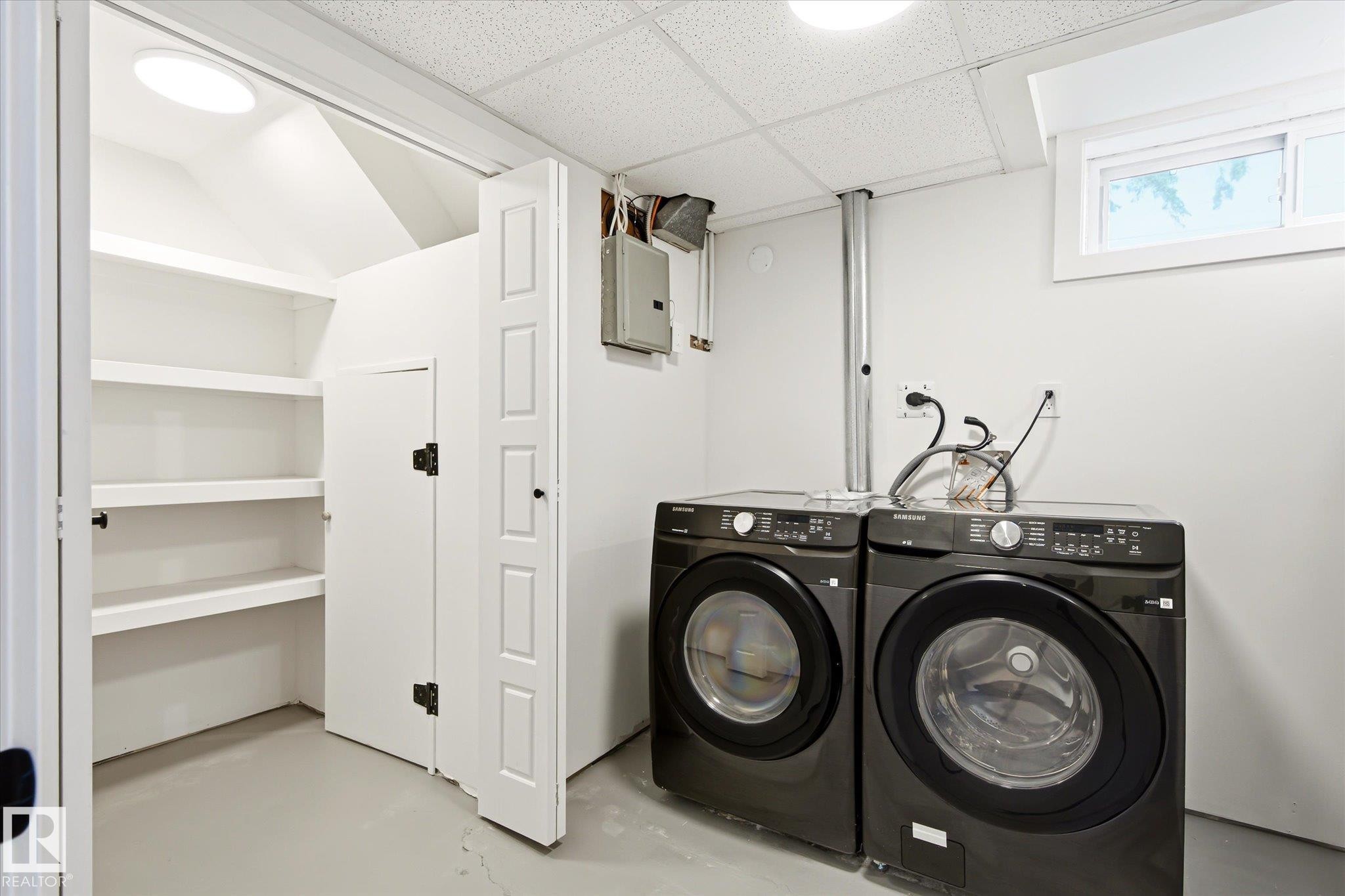 Dedicated laundry area featuring a washer and dryer, adjacent built-in shelving, white walls, and a drop ceiling - 4708 104A Avenue Nw, Edmonton, AB - Indoor Photo Showing Laundry Room