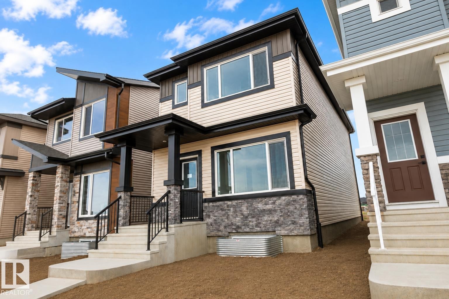 Contemporary exterior with contrasting siding, black-framed windows, stone accent detailing, and covered entry - 219 157 Avenue Ne, Edmonton, AB - Outdoor