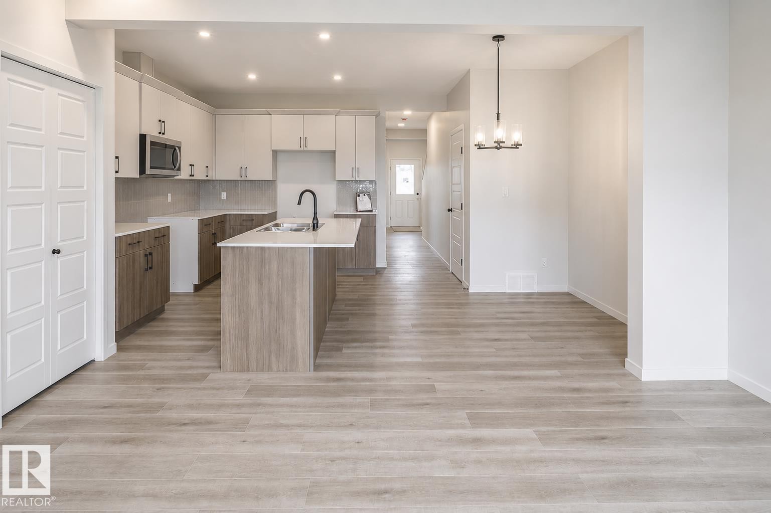 Kitchen featuring two-tone cabinetry, a central island with an integrated sink, and stainless steel appliances - 219 157 Avenue Ne, Edmonton, AB - Indoor Photo Showing Kitchen