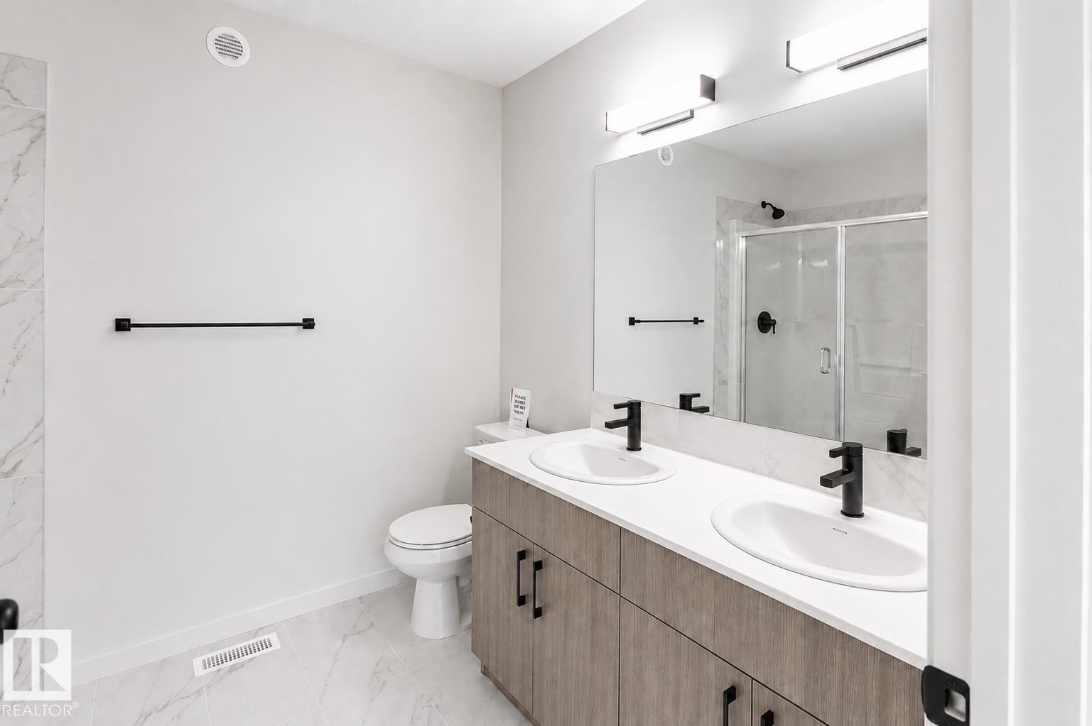 Dual vanity with undermount sinks, wood-finish cabinetry, and matte black fixtures - 219 157 Avenue Ne, Edmonton, AB - Indoor Photo Showing Bathroom