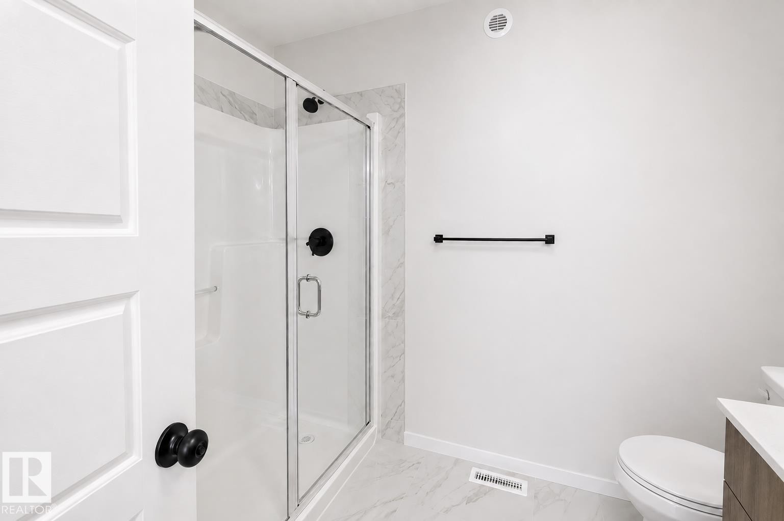 Glass-enclosed shower with matte black fixtures, white tiled walls, and a white shower pan - 219 157 Avenue Ne, Edmonton, AB - Indoor Photo Showing Bathroom