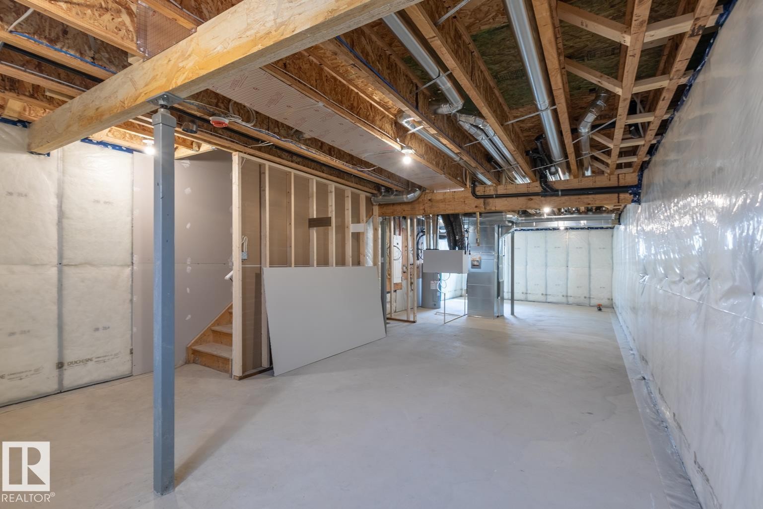 Unfinished basement with exposed wood joists and structural beams, open stud framing, and concrete flooring - 219 157 Avenue Ne, Edmonton, AB - Indoor Photo Showing Basement