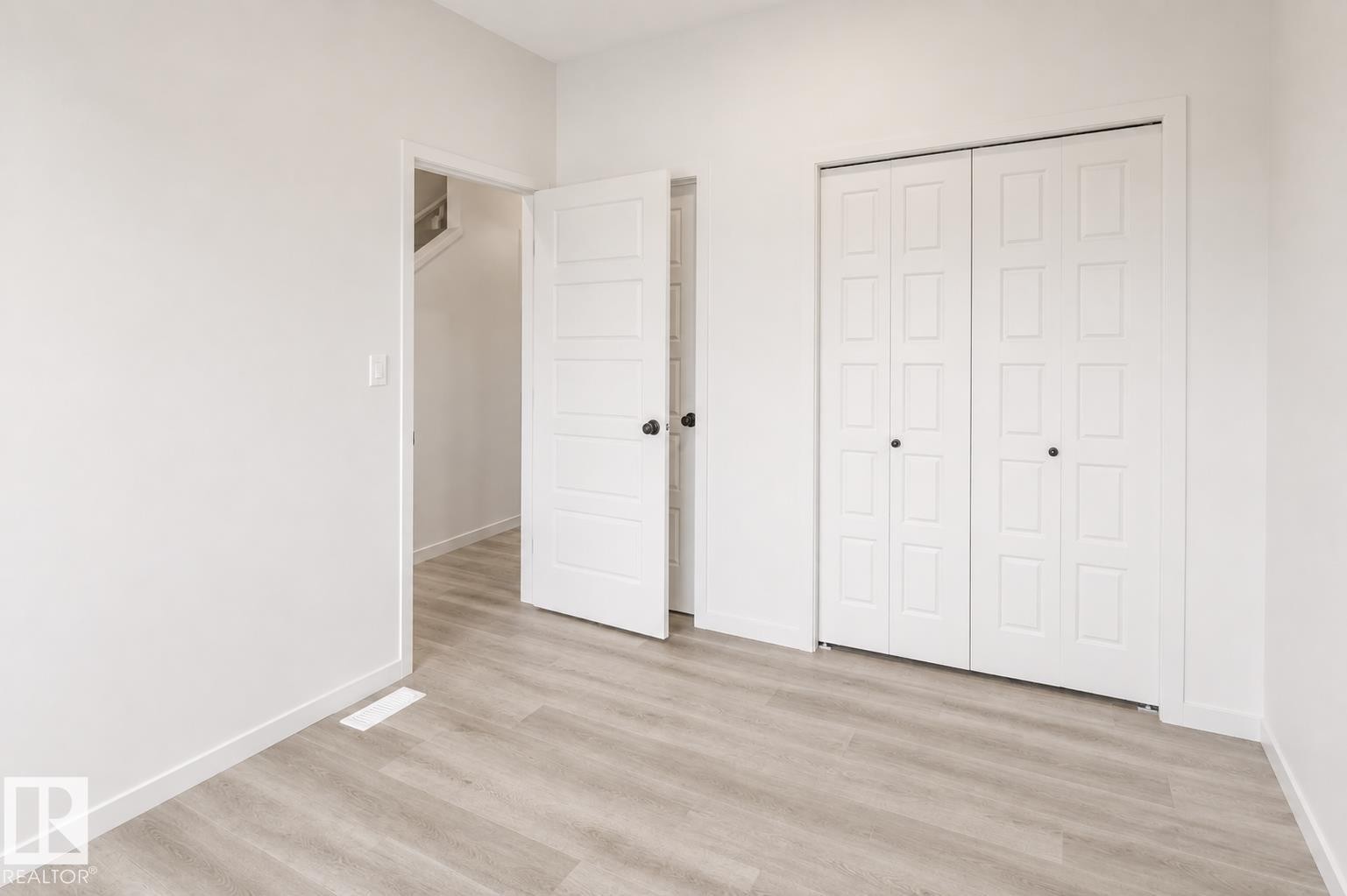 Wood-finish flooring, white paneled doors, and bi-fold closet doors - 219 157 Avenue Ne, Edmonton, AB - Indoor