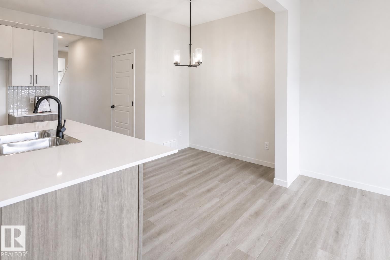 Kitchen island with white countertop and integrated stainless steel sink - 219 157 Avenue Ne, Edmonton, AB - Indoor Photo Showing Kitchen With Double Sink