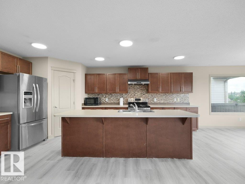 Wood-finish flooring, recessed lighting, and a kitchen island with a double basin sink - 3010 17A Ave Nw, Edmonton, AB - Indoor Photo Showing Kitchen