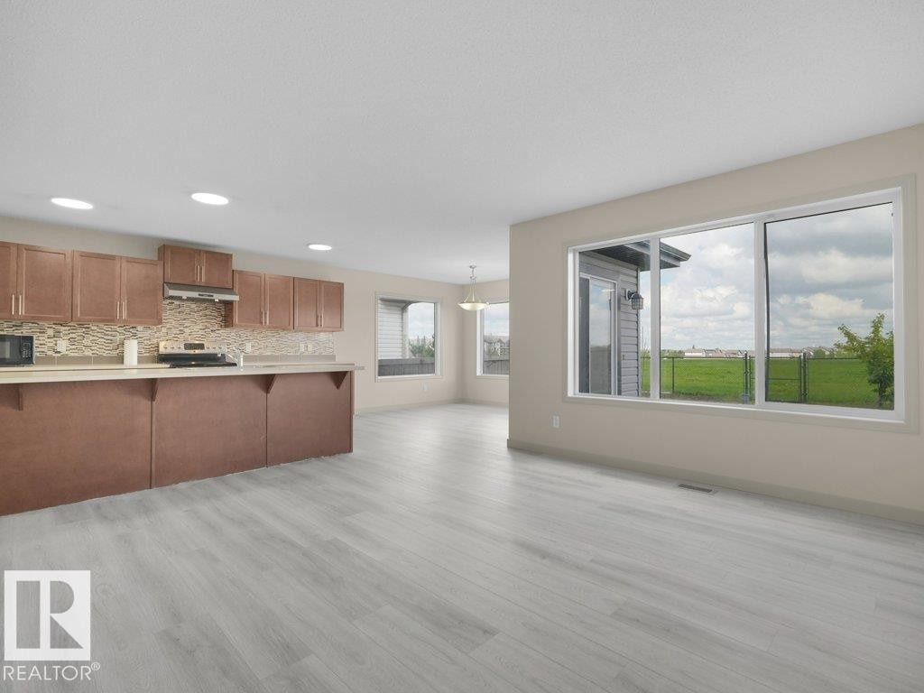 Open-concept layout featuring light wood-finish flooring, recessed lighting, and large windows - 3010 17A Ave Nw, Edmonton, AB - Indoor Photo Showing Kitchen