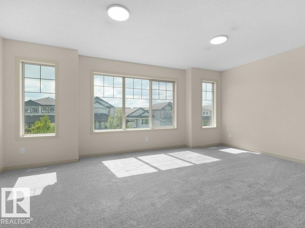 Spacious room featuring multiple windows, neutral wall tones, light gray carpeting, and two ceiling-mounted circular light fixtures - 3010 17A Ave Nw, Edmonton, AB - Indoor Photo Showing Other Room