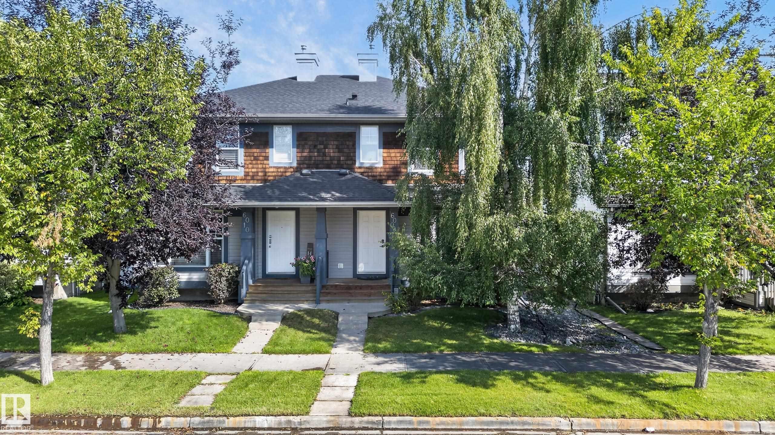 Duplex exterior featuring shingle siding, a dark roof, white entry doors, and a concrete pathway - 6008 South Terwillegar Boulevard Nw, Edmonton, AB - Outdoor