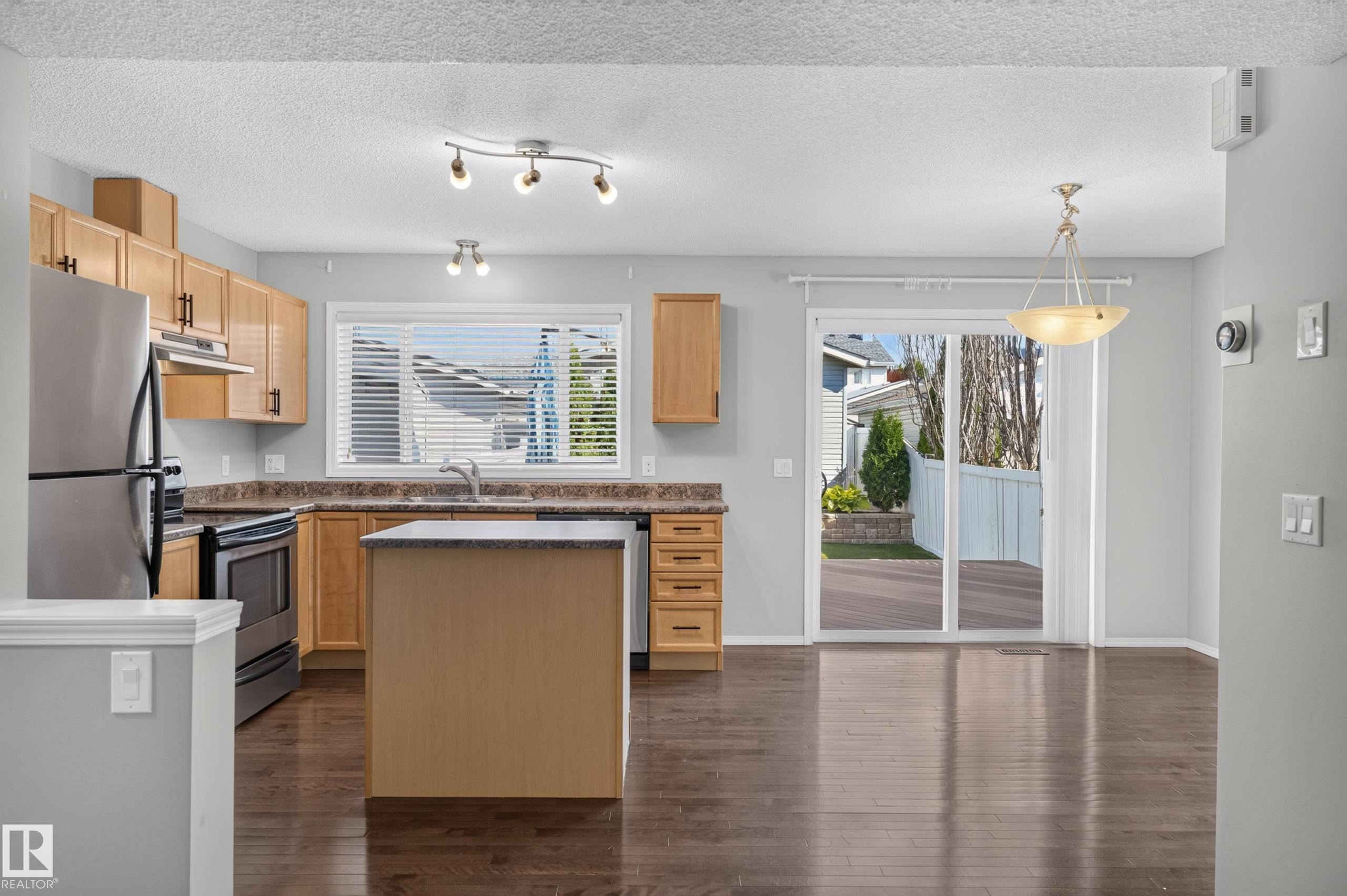 Kitchen featuring wood-finish cabinetry, stainless steel appliances, a center island with a stone-finish countertop, and dark wood-finish flooring - 6008 South Terwillegar Boulevard Nw, Edmonton, AB - Indoor Photo Showing Kitchen