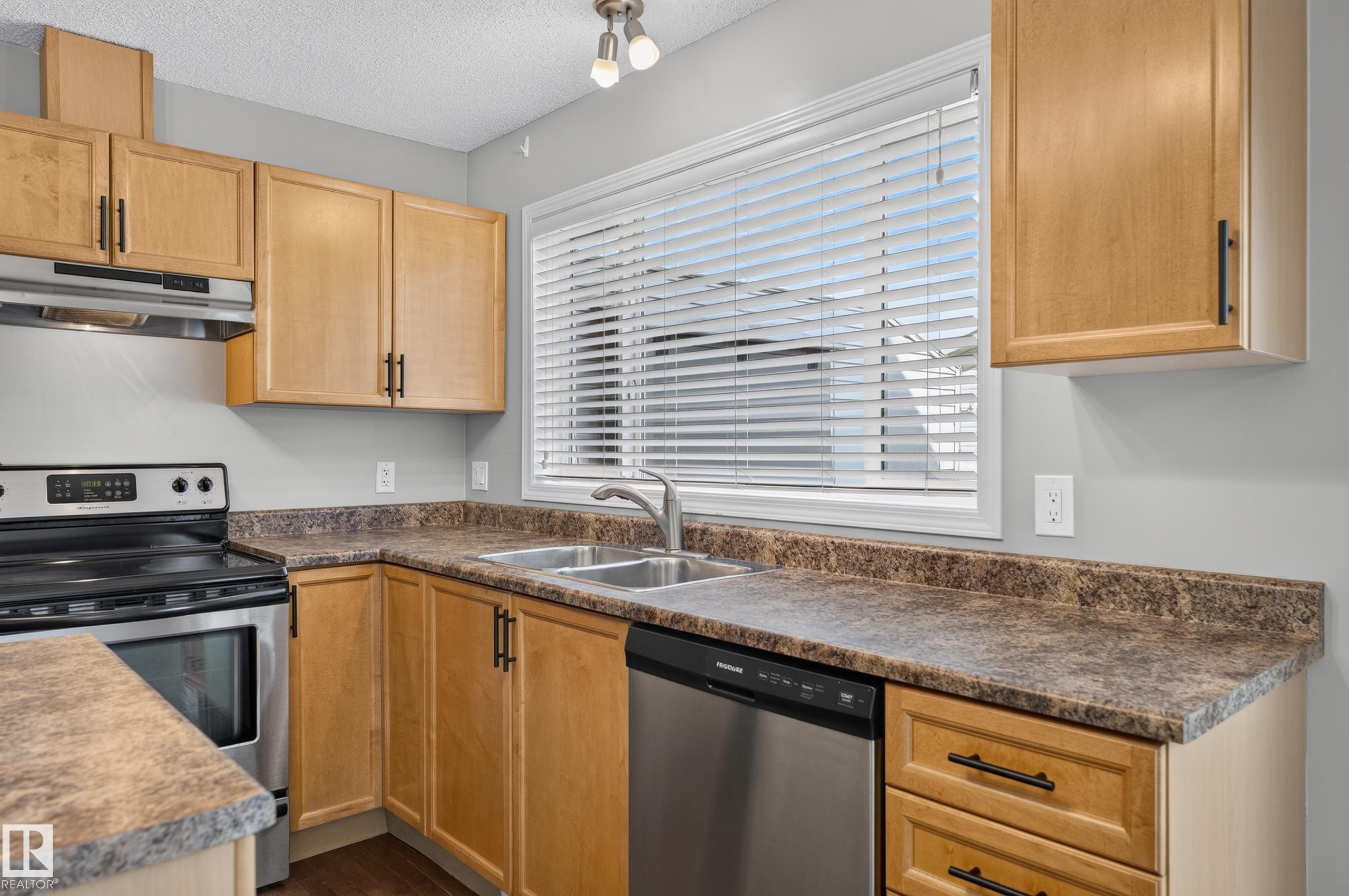 Kitchen featuring wood-finish cabinetry, stainless steel appliances, a double basin sink, and laminate countertops - 6008 South Terwillegar Boulevard Nw, Edmonton, AB - Indoor Photo Showing Kitchen With Double Sink