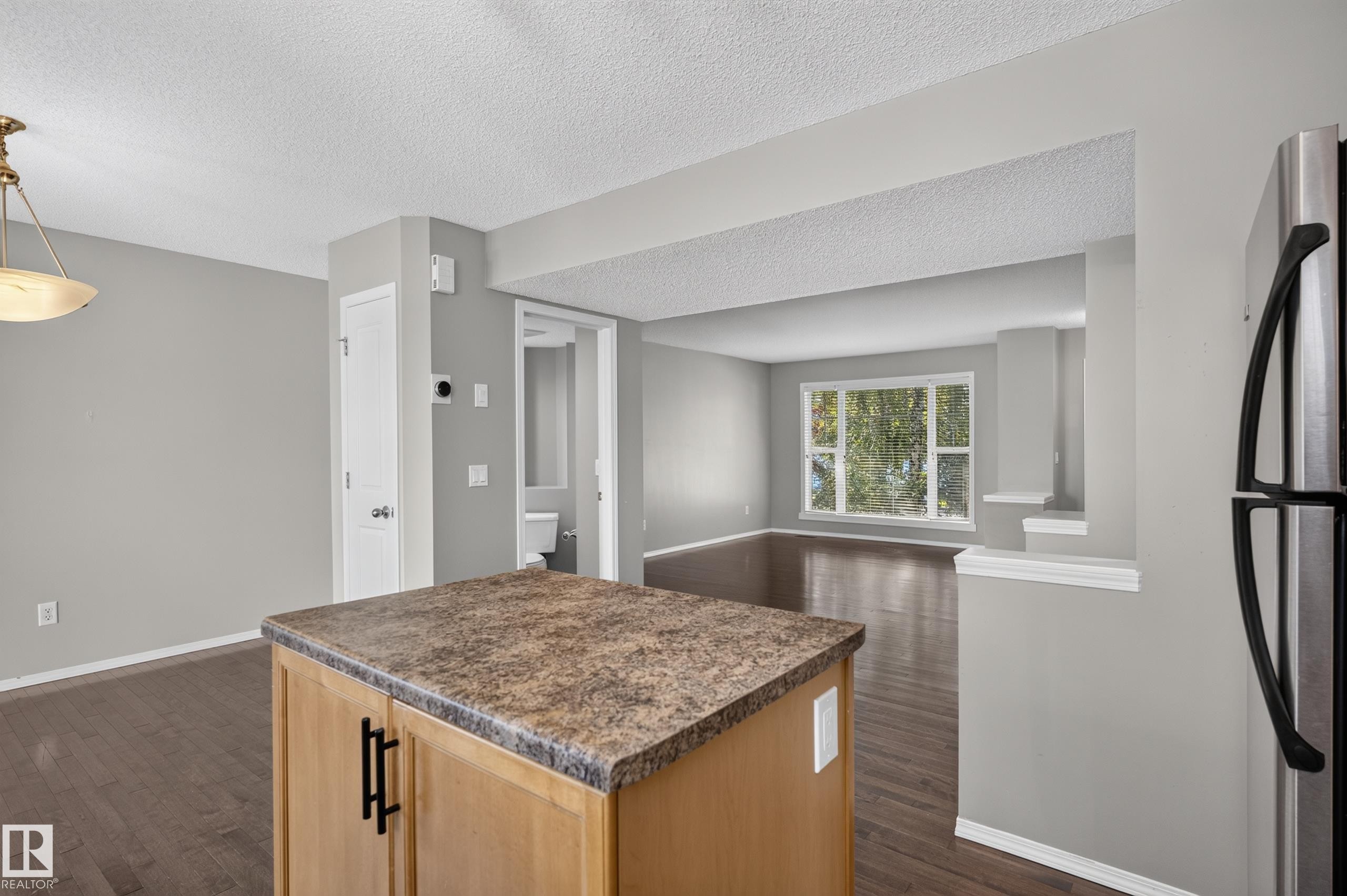 Kitchen island with stone-finish countertop, wood-finish flooring, and recessed architectural opening - 6008 South Terwillegar Boulevard Nw, Edmonton, AB - Indoor Photo Showing Kitchen