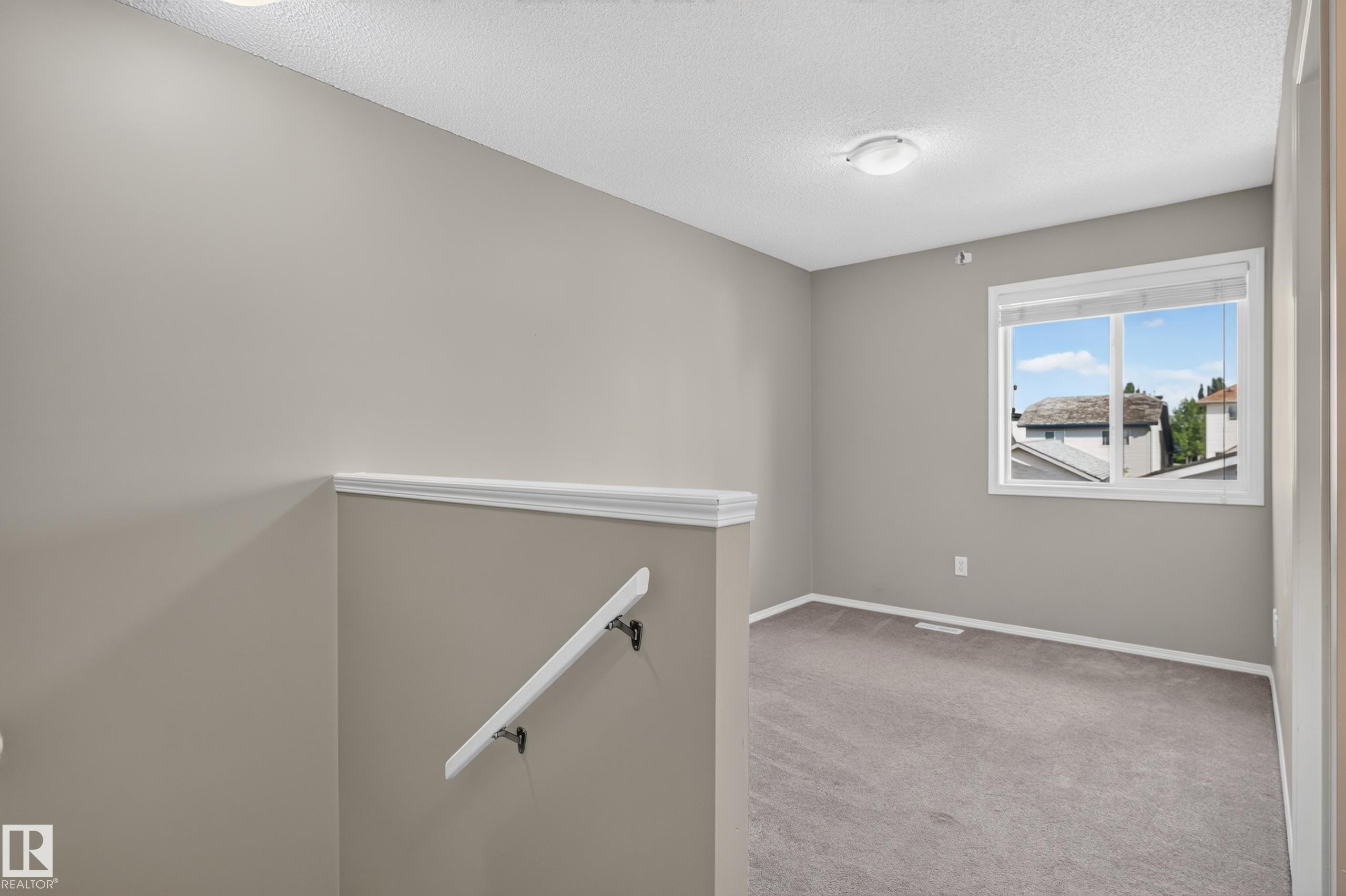 Neutral wall color, carpet flooring, window with white trim, ceiling-mounted lighting, and a white handrail - 6008 South Terwillegar Boulevard Nw, Edmonton, AB - Indoor Photo Showing Other Room