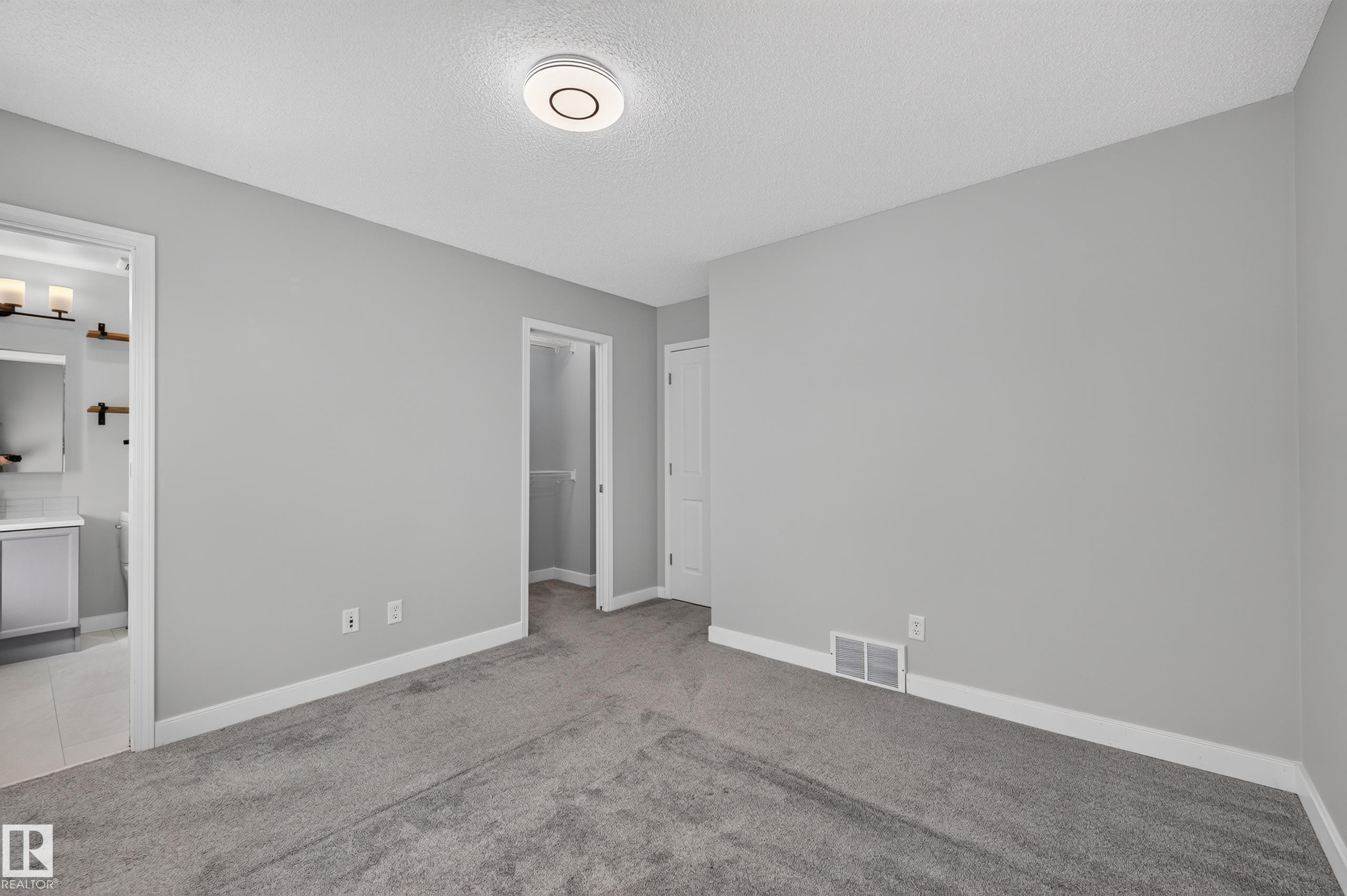 Plush gray carpeting, light gray wall paint, and a modern circular ceiling light fixture - 6008 South Terwillegar Boulevard Nw, Edmonton, AB - Indoor Photo Showing Other Room