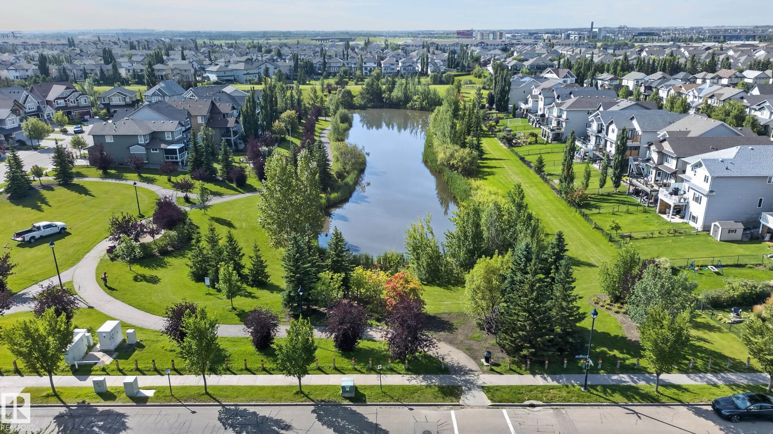 Residential area with a central pond, surrounding green spaces, and paved pathways - 6008 South Terwillegar Boulevard Nw, Edmonton, AB - Outdoor With View
