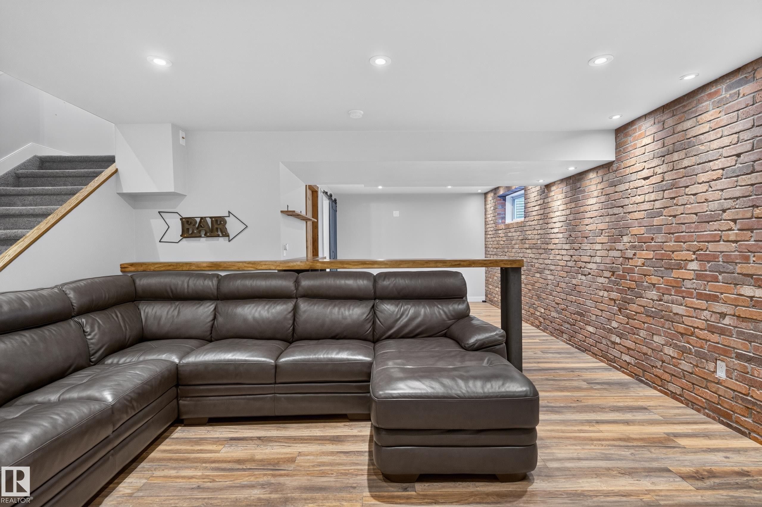 Exposed brick accent wall, recessed ceiling lighting, wood-finish flooring, built-in bar counter, and carpeted staircase - 6008 South Terwillegar Boulevard Nw, Edmonton, AB - Indoor Photo Showing Living Room