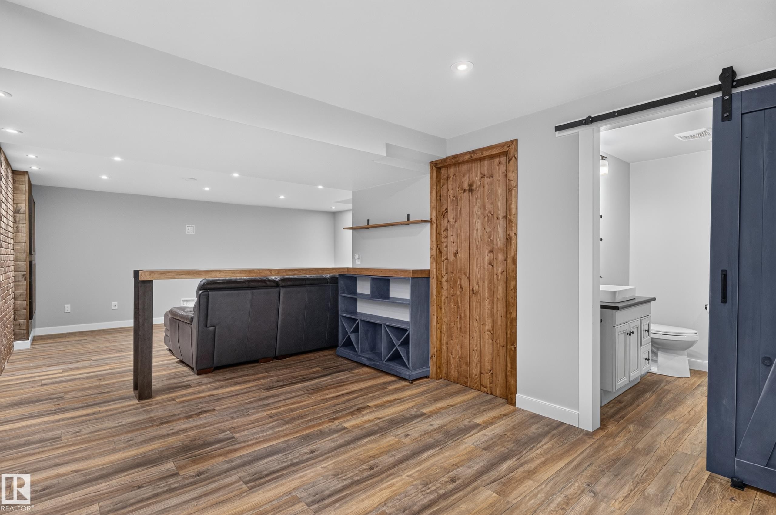 Wood-finish flooring throughout, complemented by a brick accent wall and recessed lighting - 6008 South Terwillegar Boulevard Nw, Edmonton, AB - Indoor