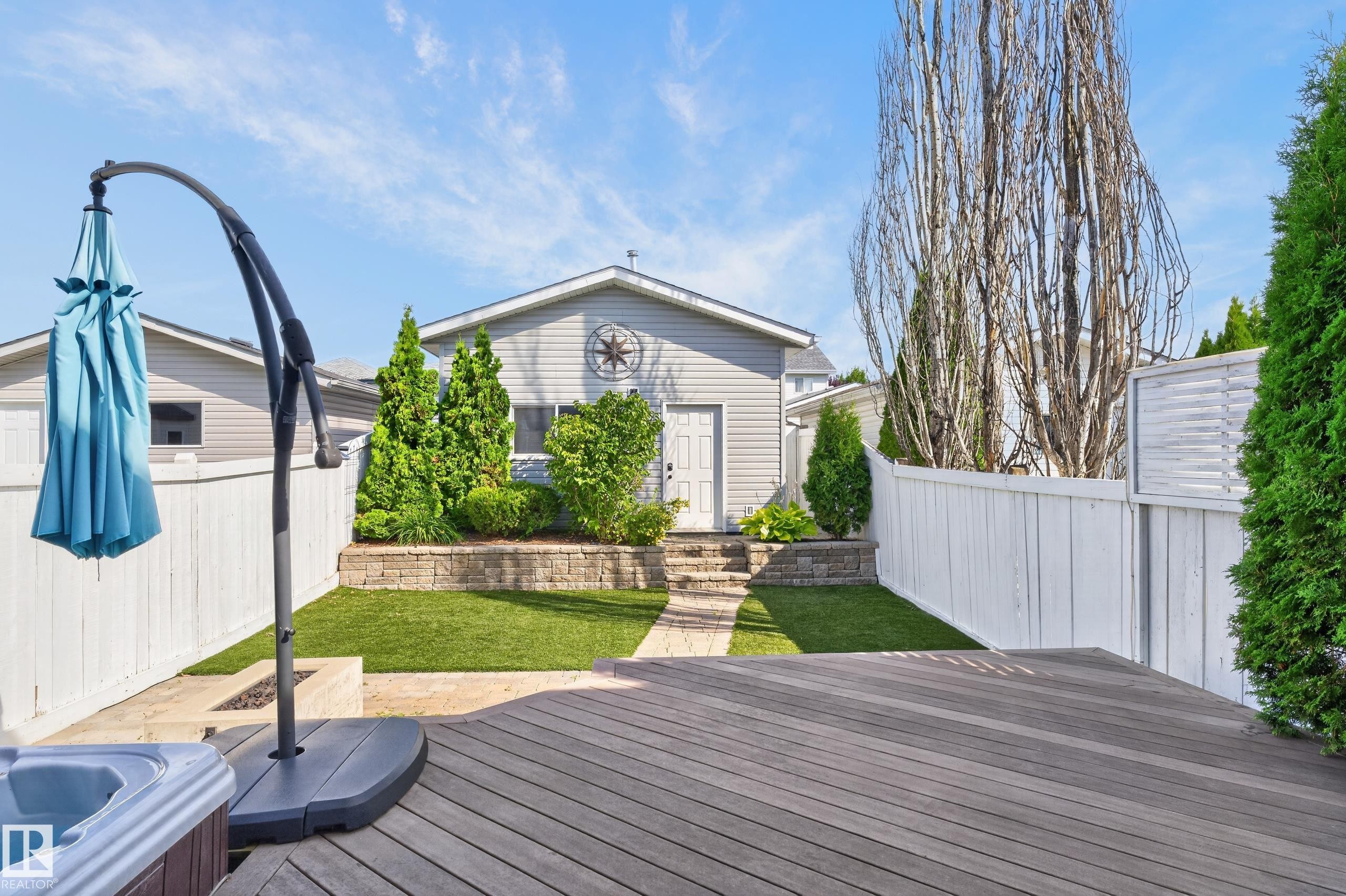 Expansive backyard featuring a composite deck, artificial turf, tiered landscaping, and privacy fencing - 6008 South Terwillegar Boulevard Nw, Edmonton, AB - Outdoor With Deck Patio Veranda