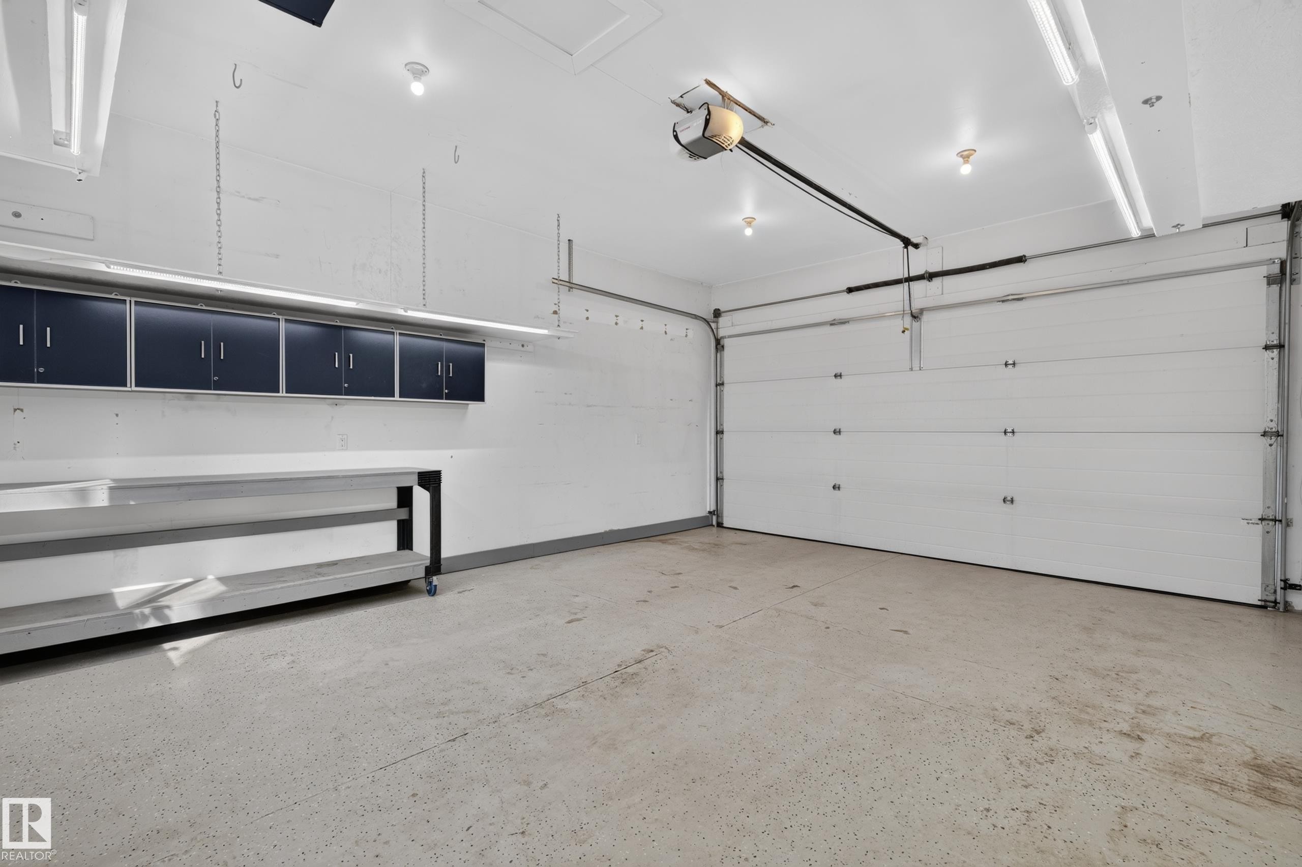 Attached overhead cabinetry, workbench, garage door opener, and epoxy flooring - 6008 South Terwillegar Boulevard Nw, Edmonton, AB - Indoor Photo Showing Garage