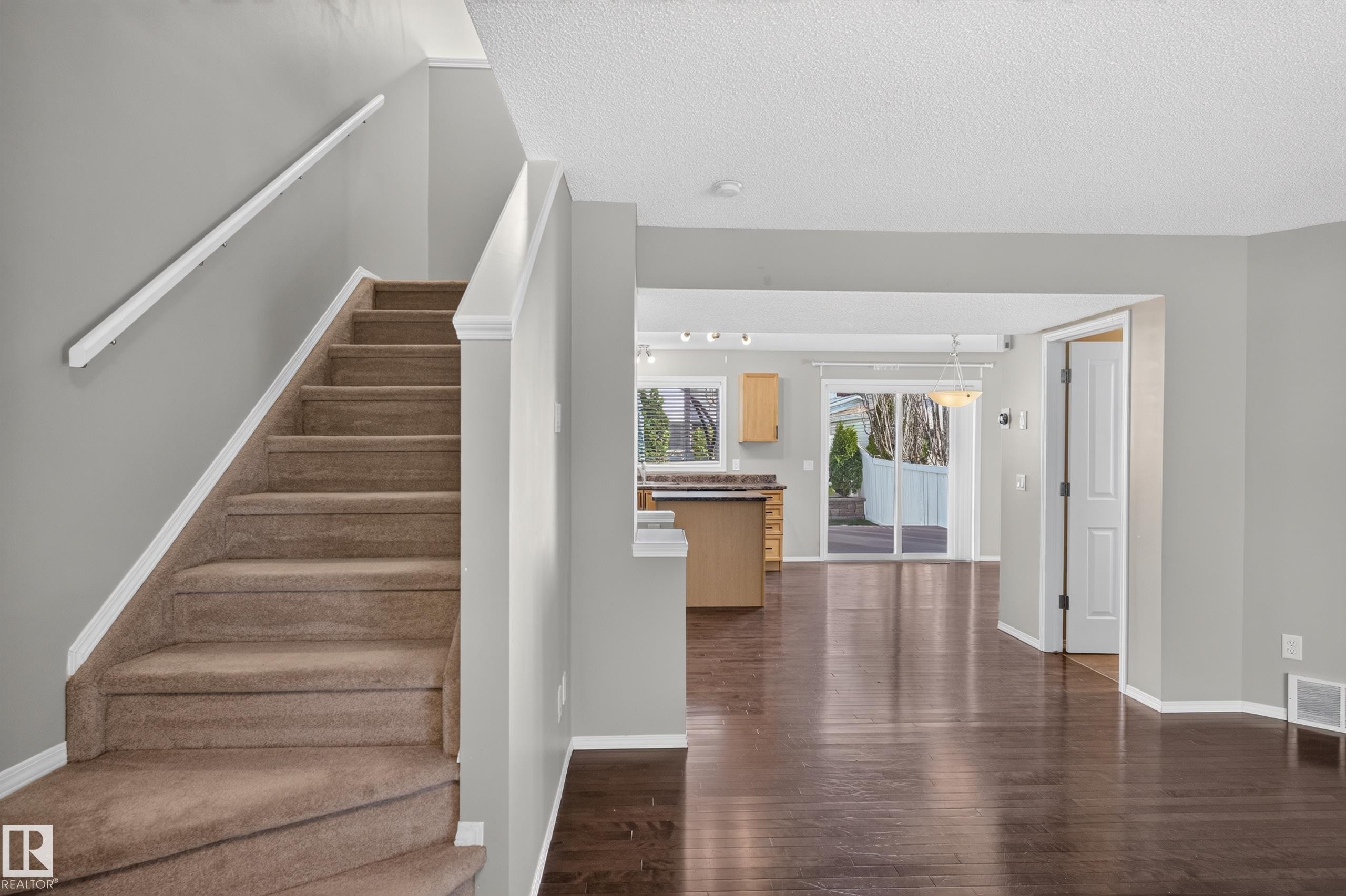 Carpeted staircase with white trim, wood-finish flooring, recessed lighting, and a sliding glass door to the exterior - 6008 South Terwillegar Boulevard Nw, Edmonton, AB - Indoor Photo Showing Other Room