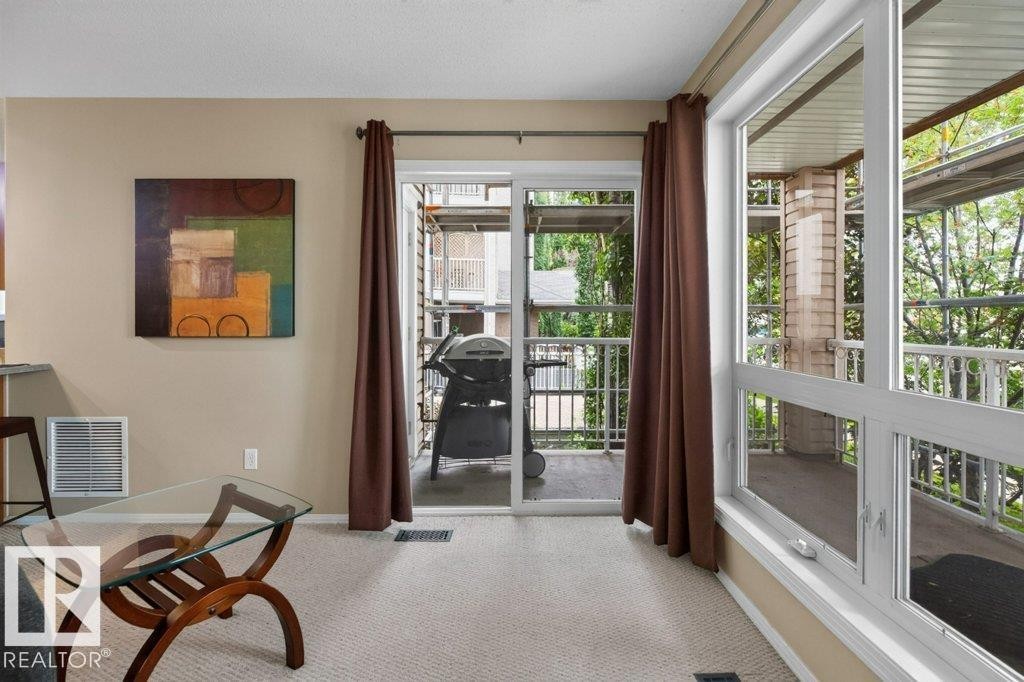 Light-toned carpeting, expansive window, sliding glass door, and exterior balcony - #201 10528 77 Av Nw, Edmonton, AB - Indoor Photo Showing Other Room