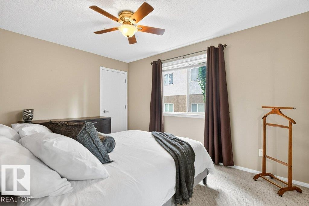 Ceiling fan with integrated lighting, neutral wall paint, white trim, and light-colored carpeting - #201 10528 77 Av Nw, Edmonton, AB - Indoor Photo Showing Bedroom