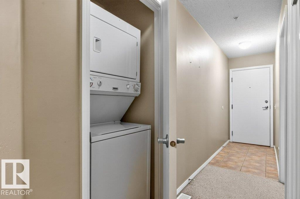 Stackable laundry appliances within a dedicated closet - #201 10528 77 Av Nw, Edmonton, AB - Indoor Photo Showing Laundry Room