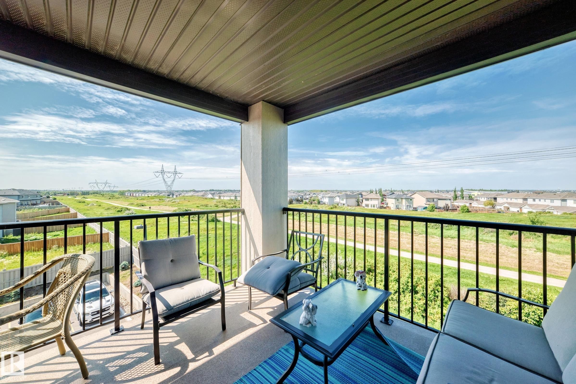 Covered outdoor balcony with a black metal railing and concrete flooring - #401 5390 Chappelle Rd Sw, Edmonton, AB