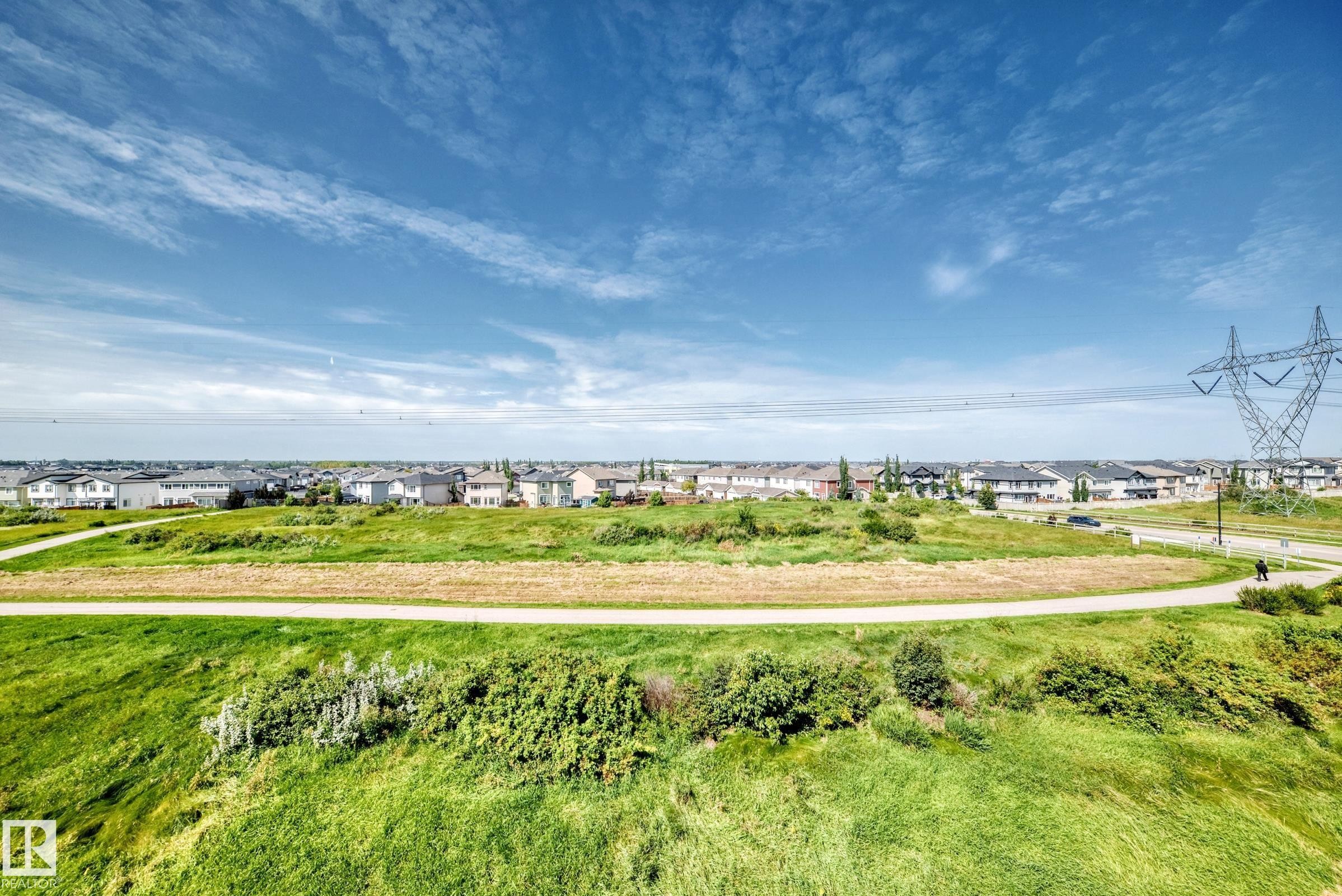Expansive green space with walking path and residential homes in the background - #401 5390 Chappelle Rd Sw, Edmonton, AB