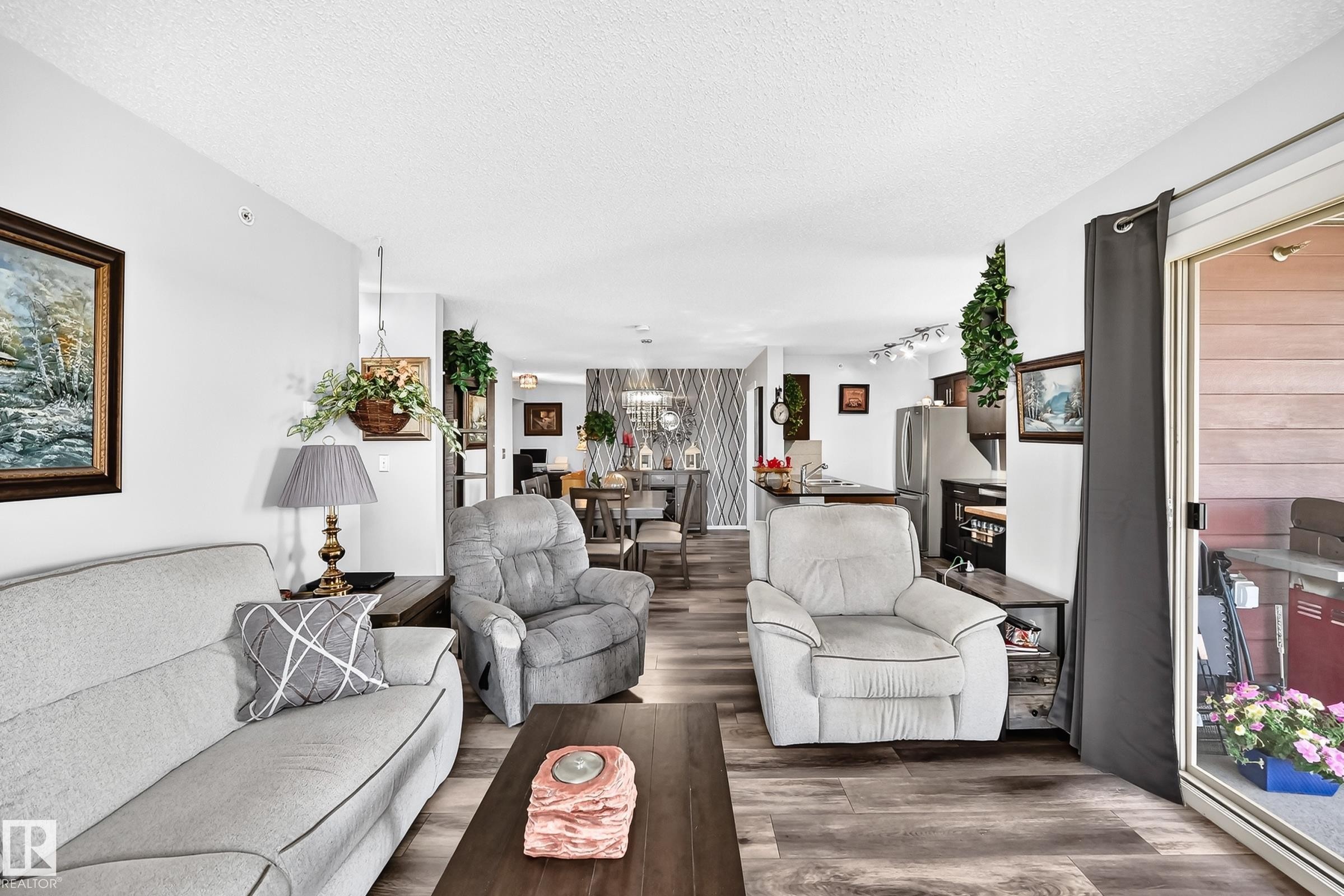 Open-concept living area featuring wood-finish flooring, recessed lighting, and a sliding glass door - #401 5390 Chappelle Rd Sw, Edmonton, AB