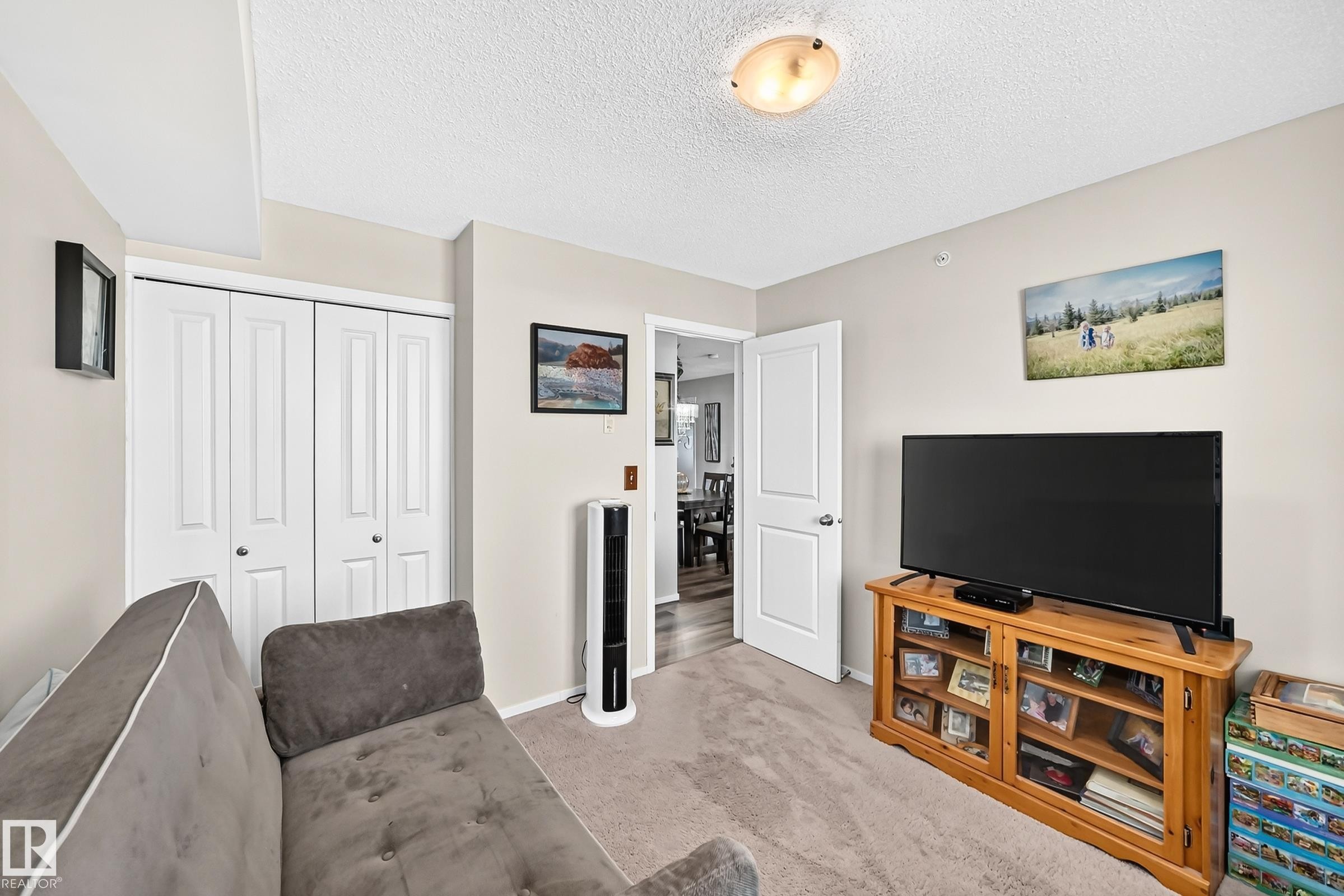 Neutral wall color, carpeted flooring, white bi-fold closet doors, white interior door, and flush mount ceiling light fixture - #401 5390 Chappelle Rd Sw, Edmonton, AB