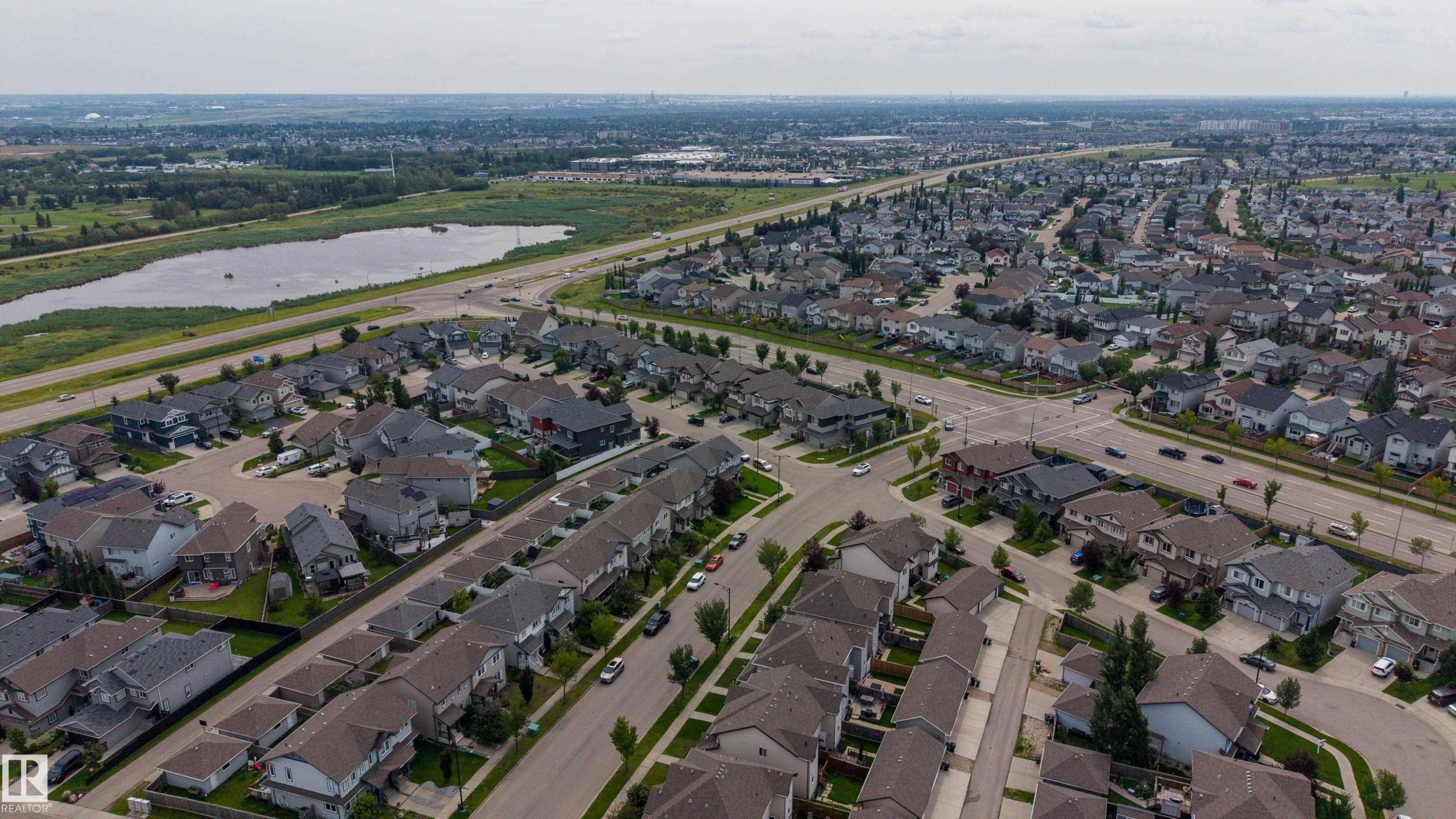 Expansive neighborhood featuring residential homes, paved streets, and a large natural water body - 124 Cy Becker Boulevard Nw, Edmonton, AB - Outdoor With View