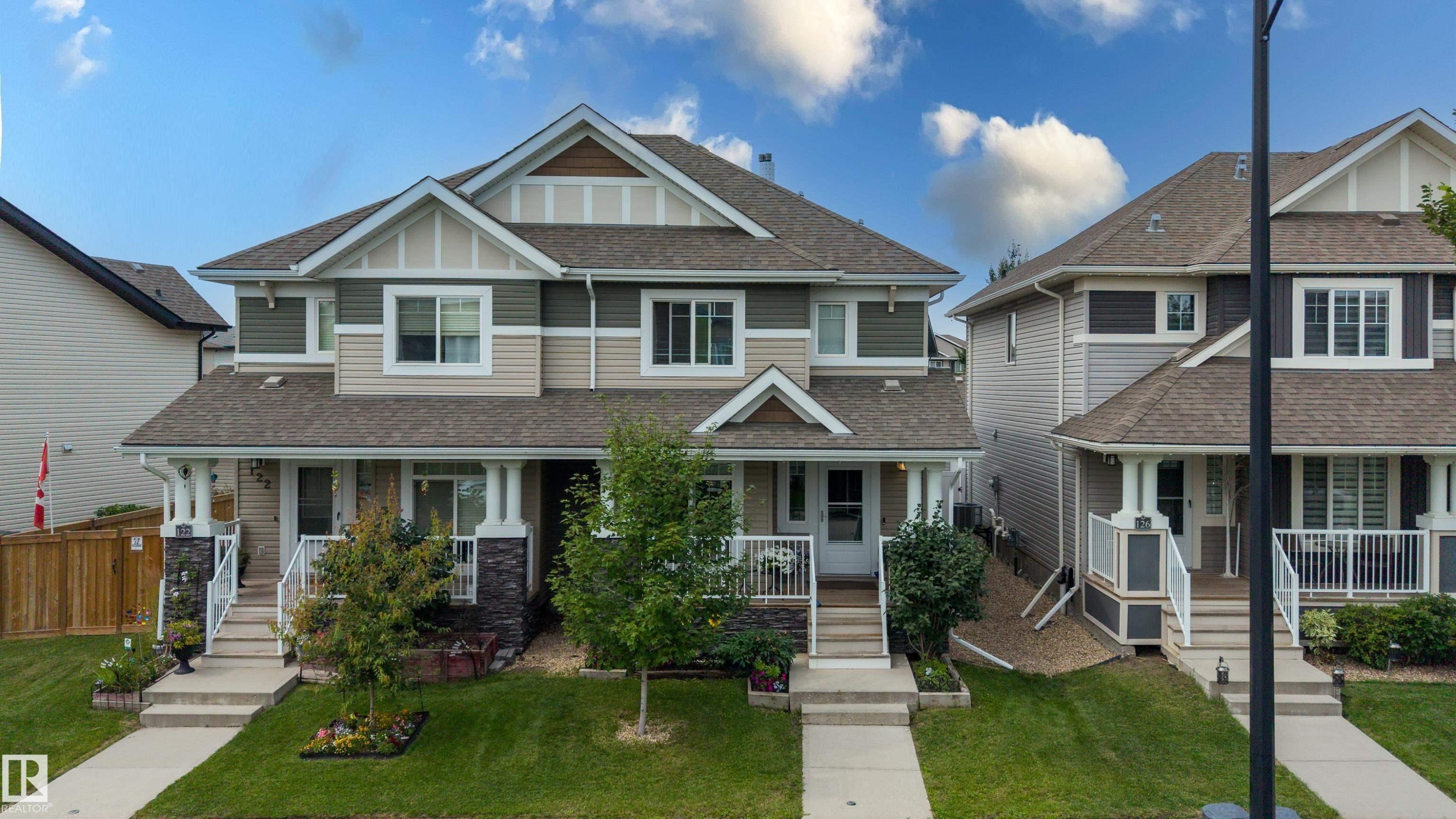 Two-story duplex with a multi-textured exterior, featuring stone veneer accents and white trim - 124 Cy Becker Boulevard Nw, Edmonton, AB - Outdoor With Deck Patio Veranda With Facade