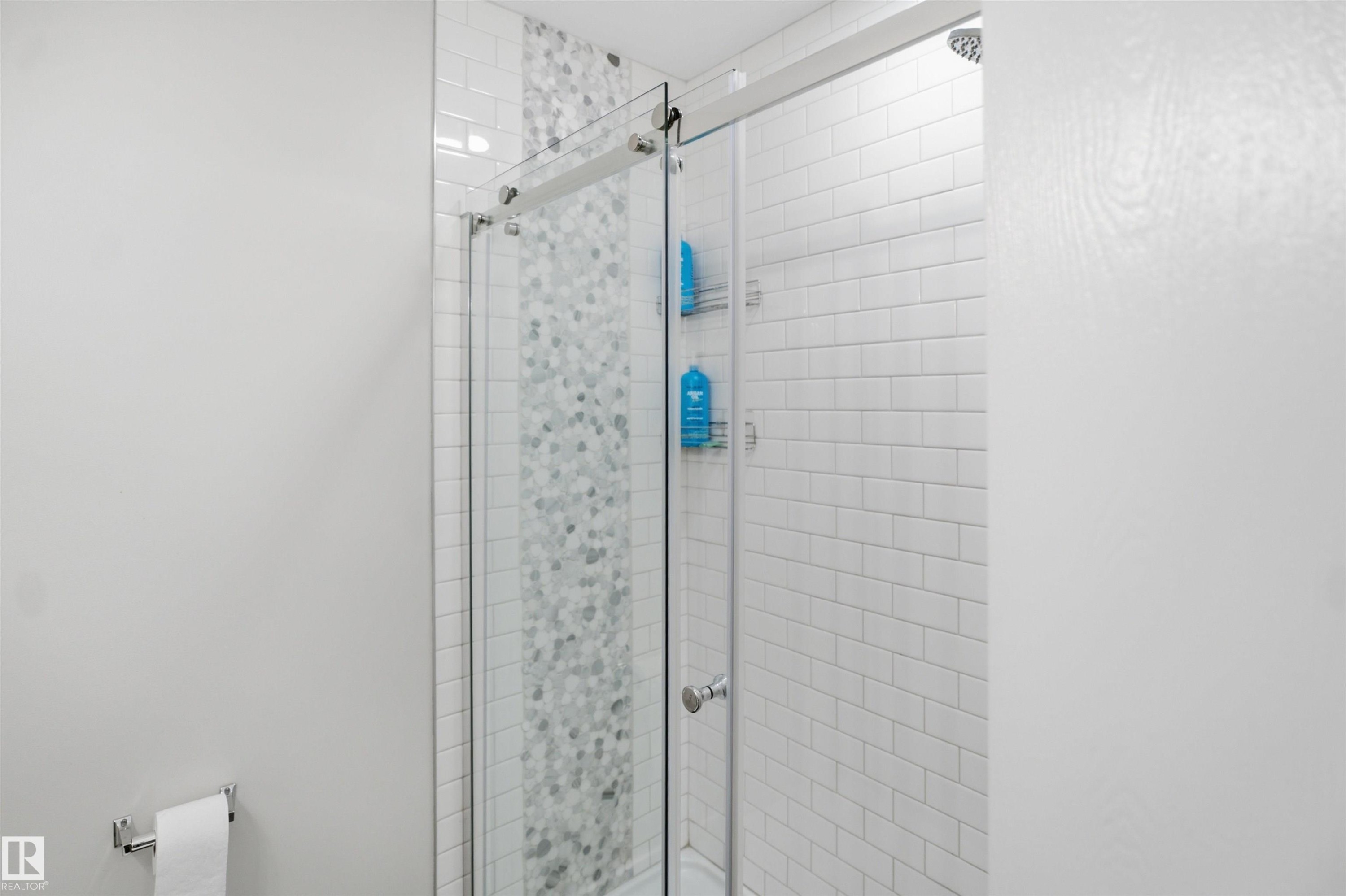 Glass-enclosed shower with a sliding door, white subway tile surround, and a mosaic tile accent strip - 3515 20 Ave Nw, Edmonton, AB