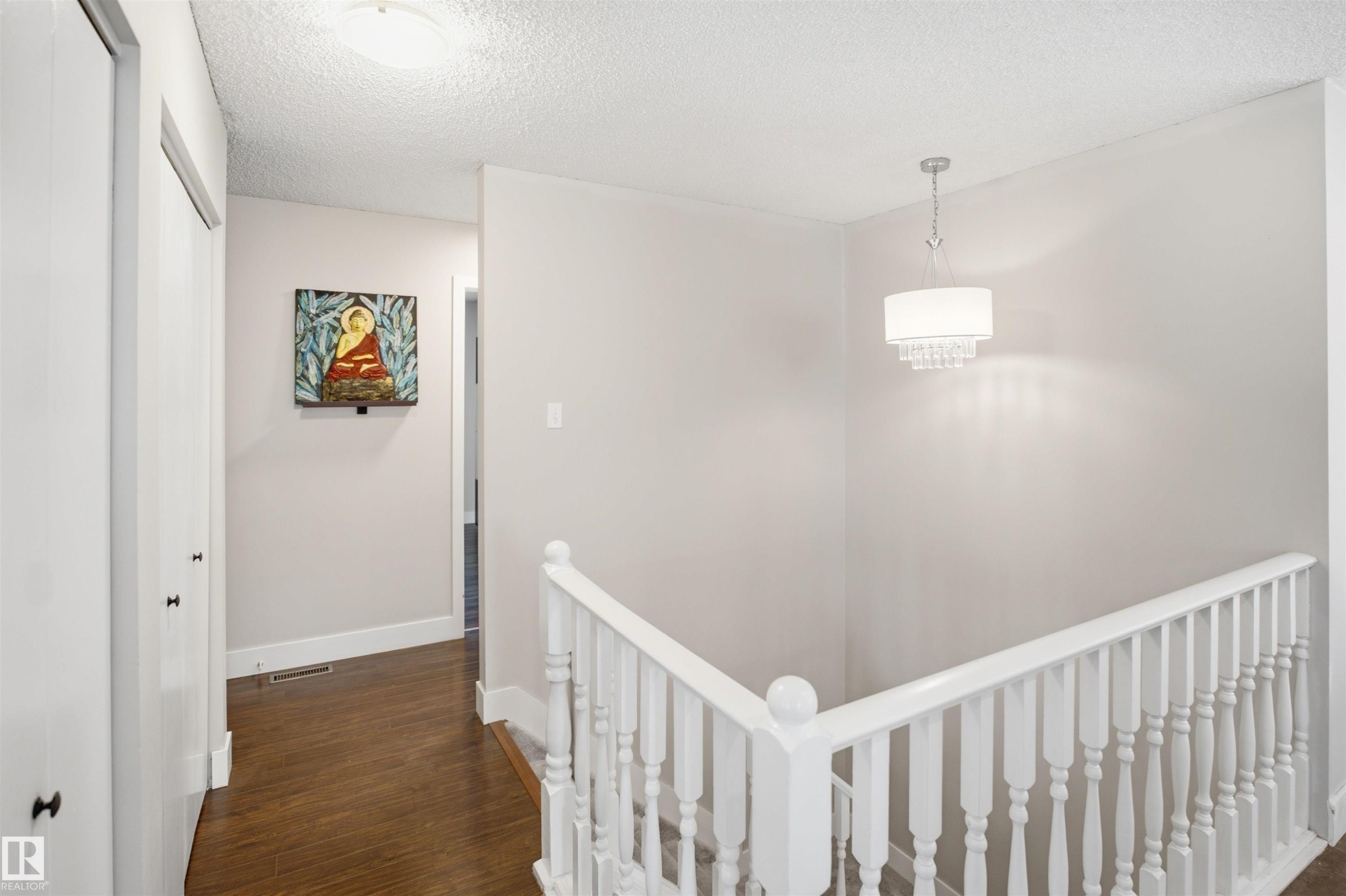 Wood-finish flooring with white trim, white paneled doors, and a decorative white chandelier - 3515 20 Ave Nw, Edmonton, AB