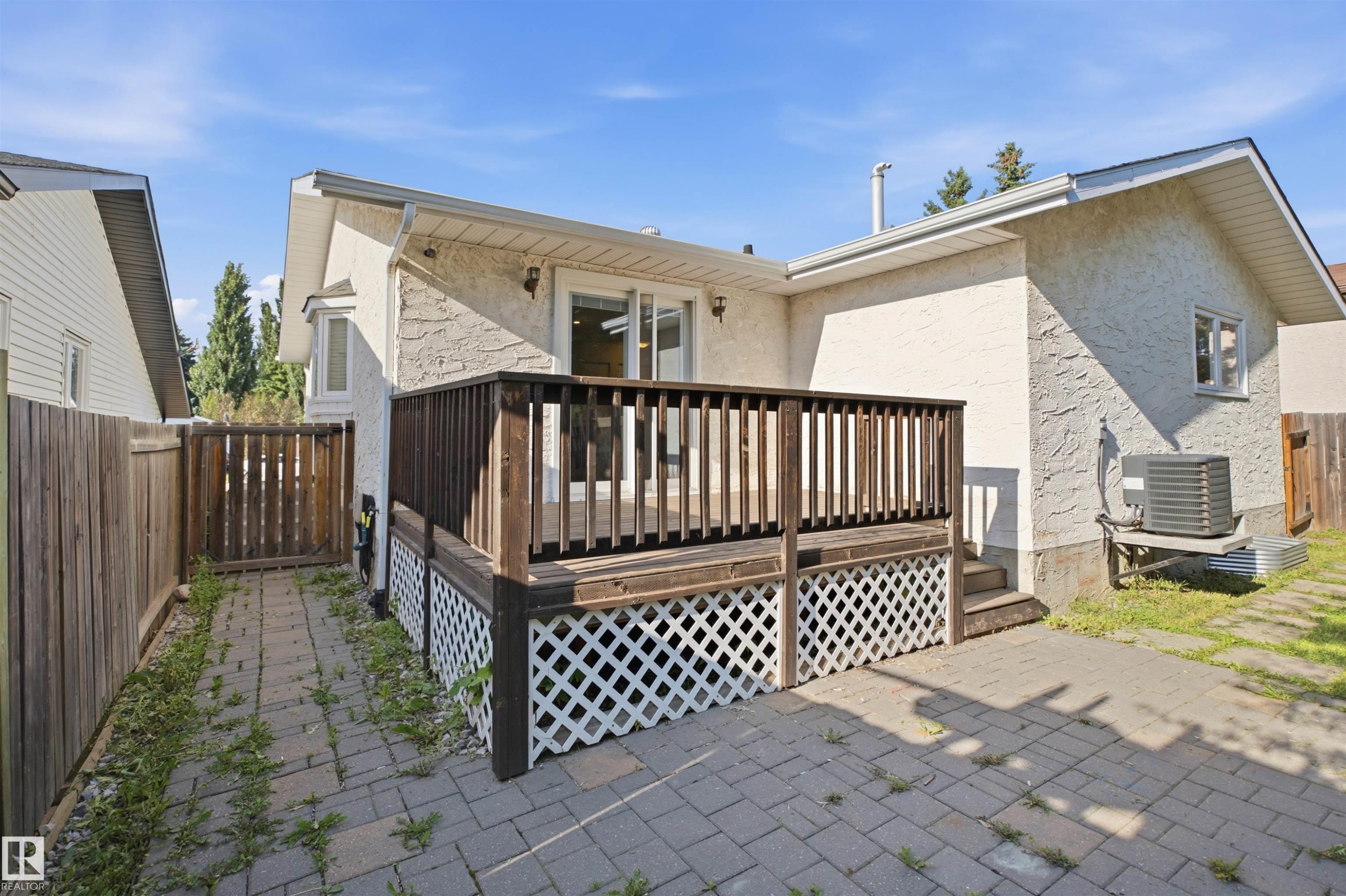 Wood deck with lattice skirting, paver patio, stucco exterior, and bay window - 3515 20 Ave Nw, Edmonton, AB