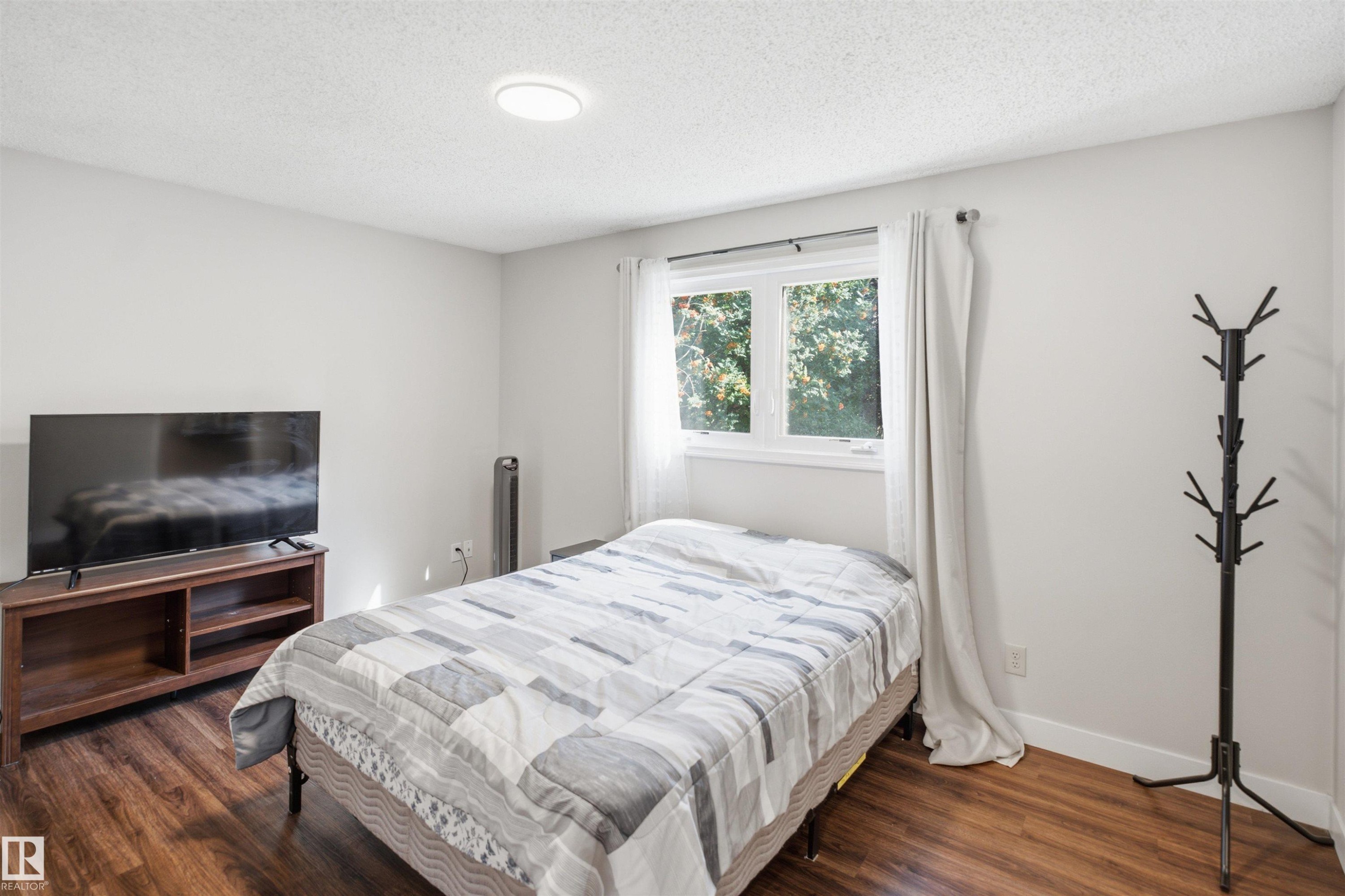 Bedroom 2- Room featuring wood-finish flooring, a white ceiling with a flush-mount light fixture, and a window with white trim - 3515 20 Ave Nw, Edmonton, AB