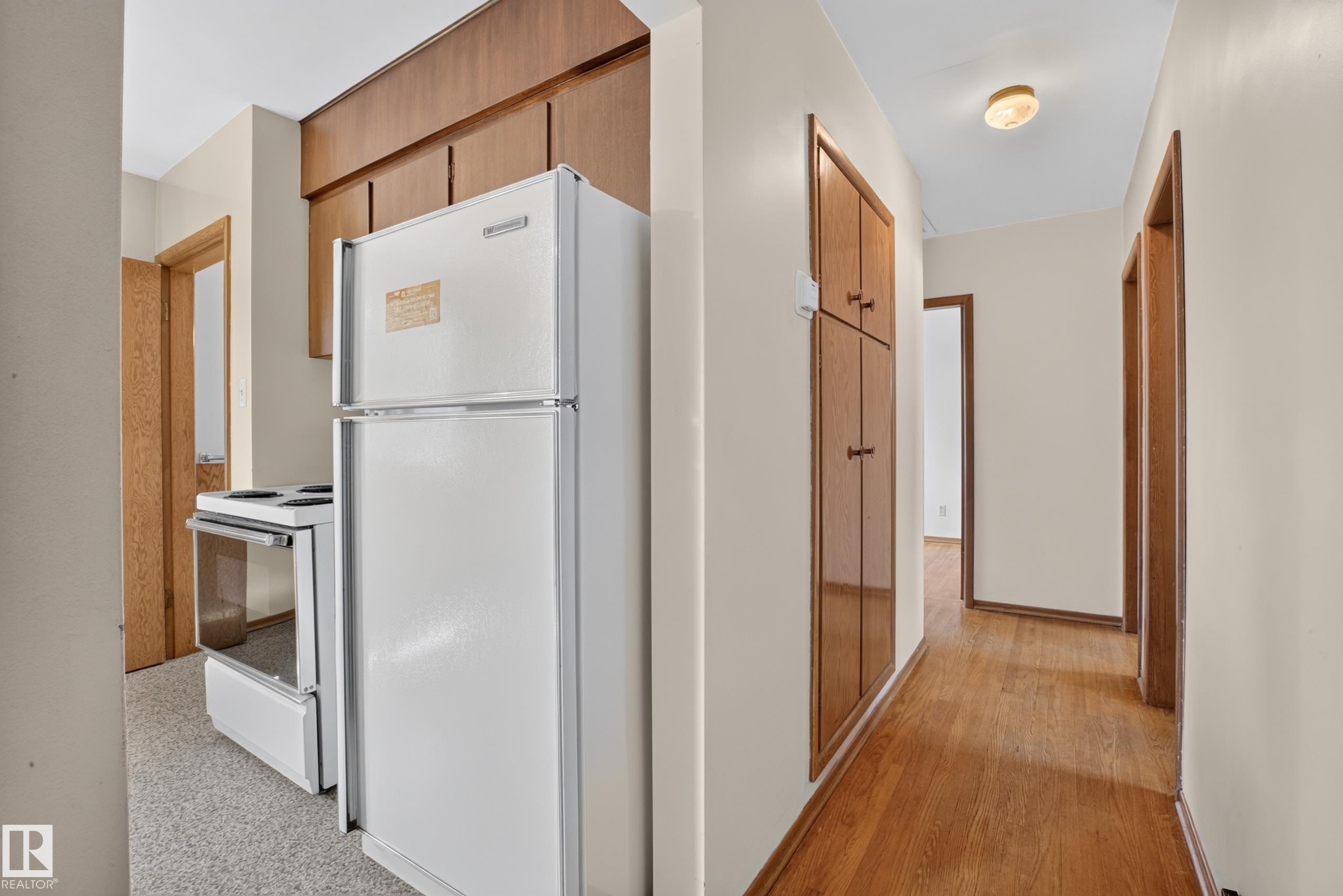 Wood-finish flooring throughout the hallway, built-in cabinetry, and a ceiling-mounted light fixture - 16009 93A Avenue Nw, Edmonton, AB - Indoor