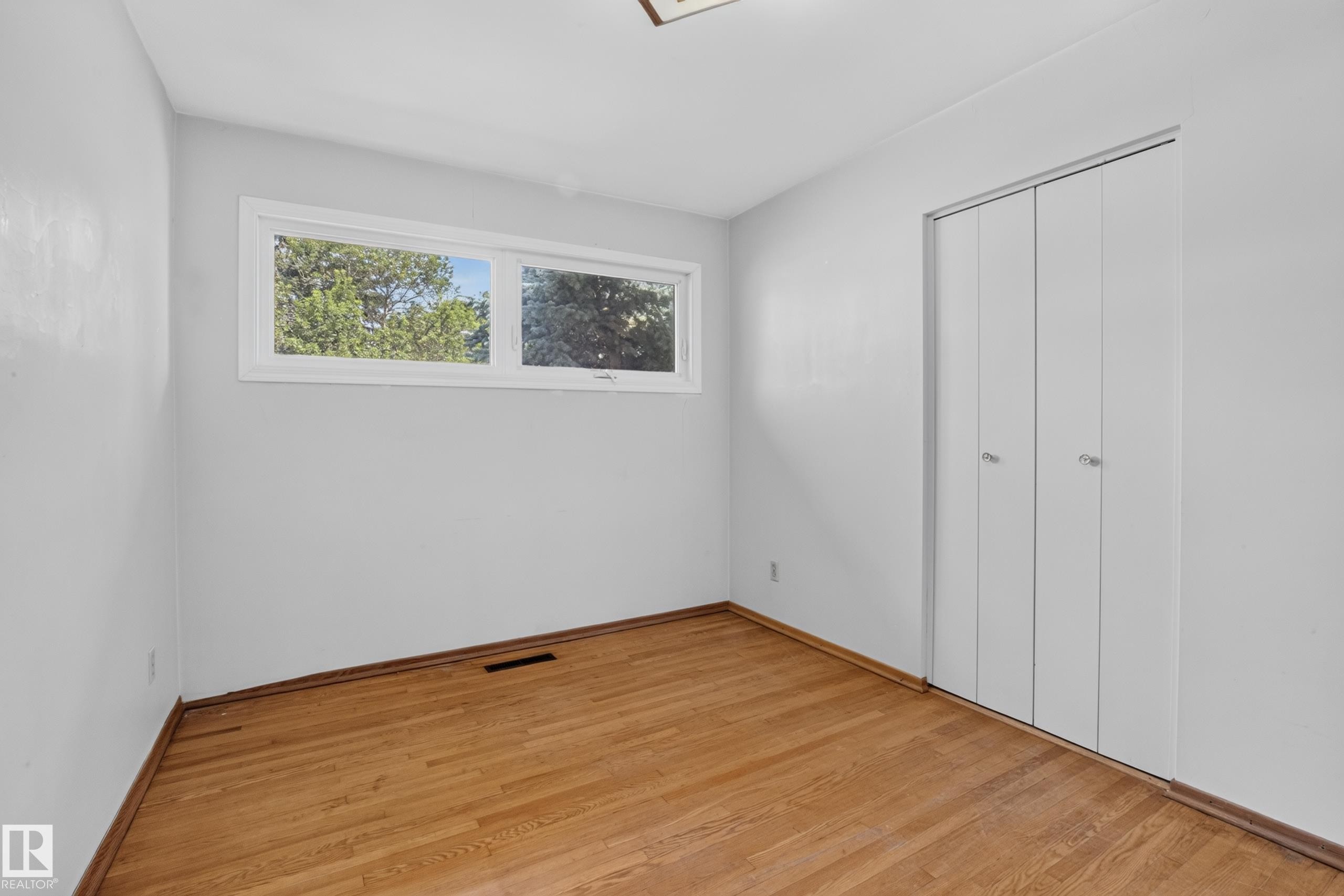 Hardwood flooring with bi-fold closet doors and a rectangular window - 16009 93A Avenue Nw, Edmonton, AB - Indoor Photo Showing Other Room